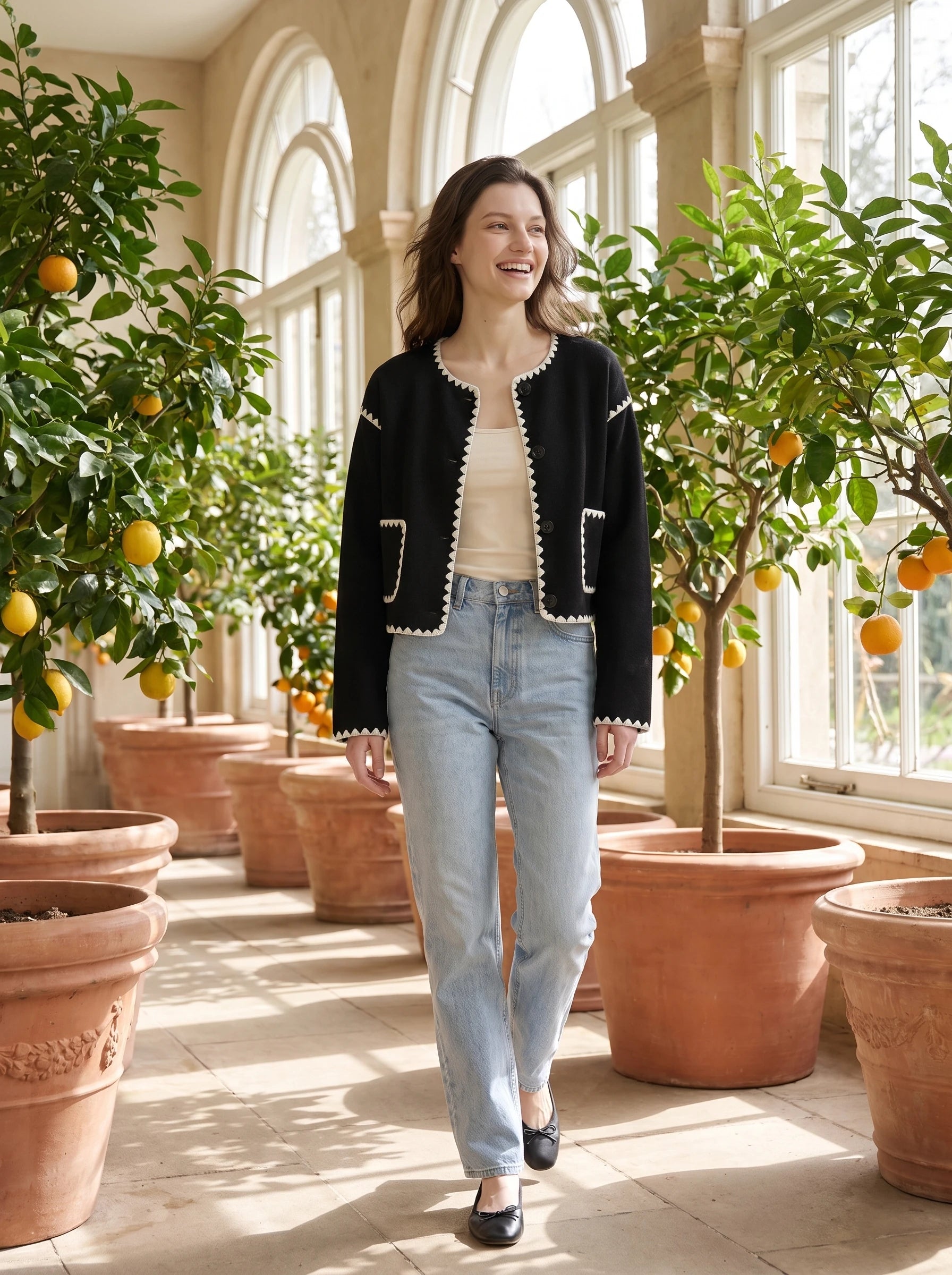 Veste courte festonnée noire Huguette, portée dans une orangerie aux agrumes