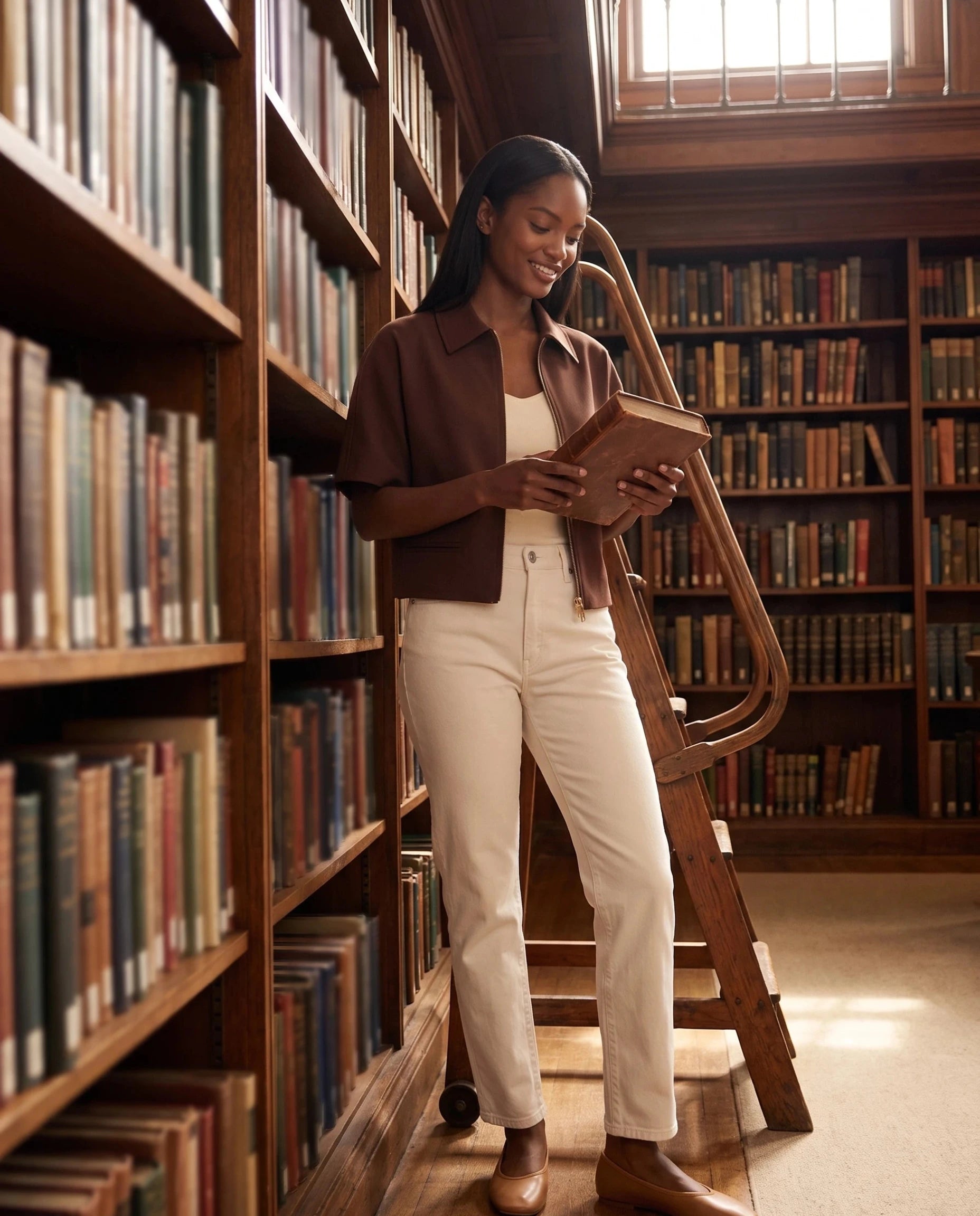 Veste courte zippée chocolat Gilberte, portée dans une bibliothèque ancienne