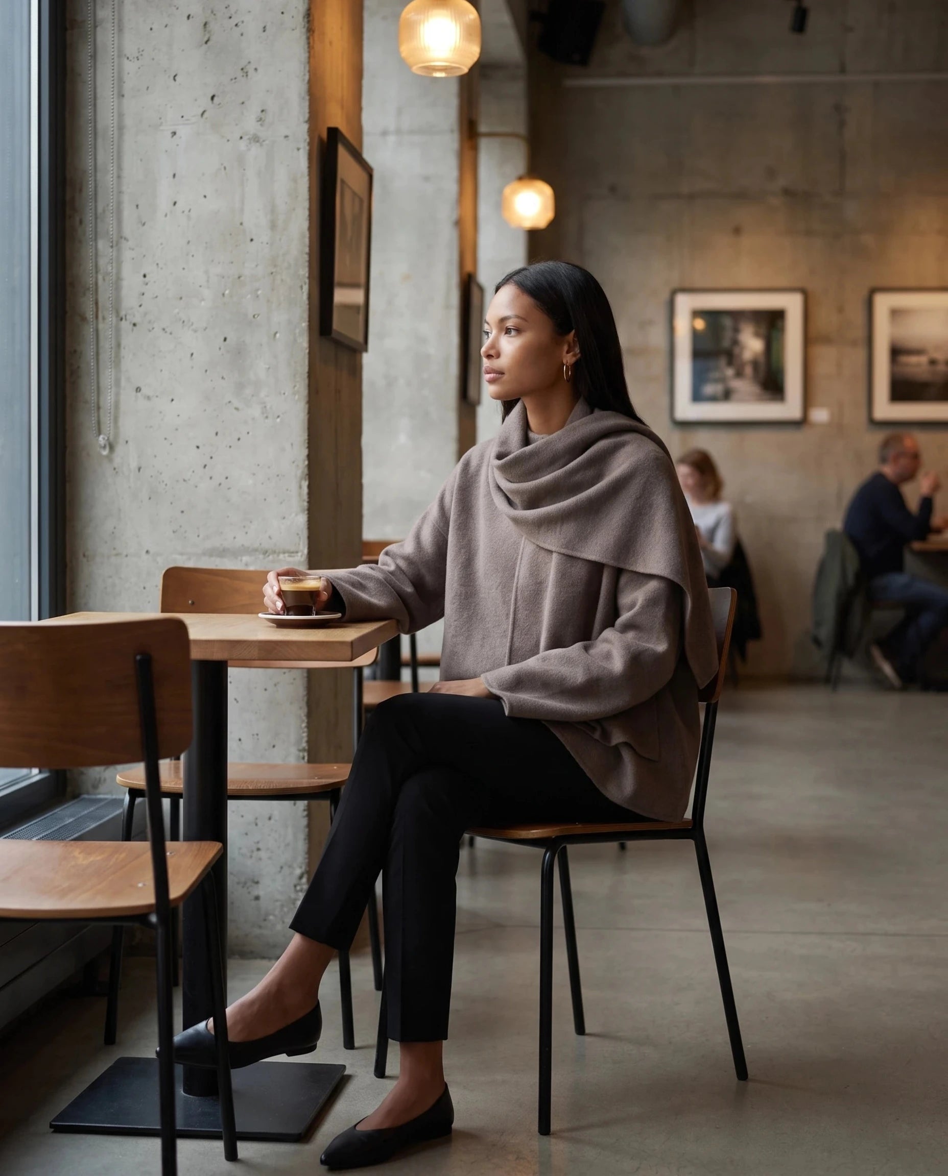 Veste en maille taupe Méline, portée assise dans un café-galerie