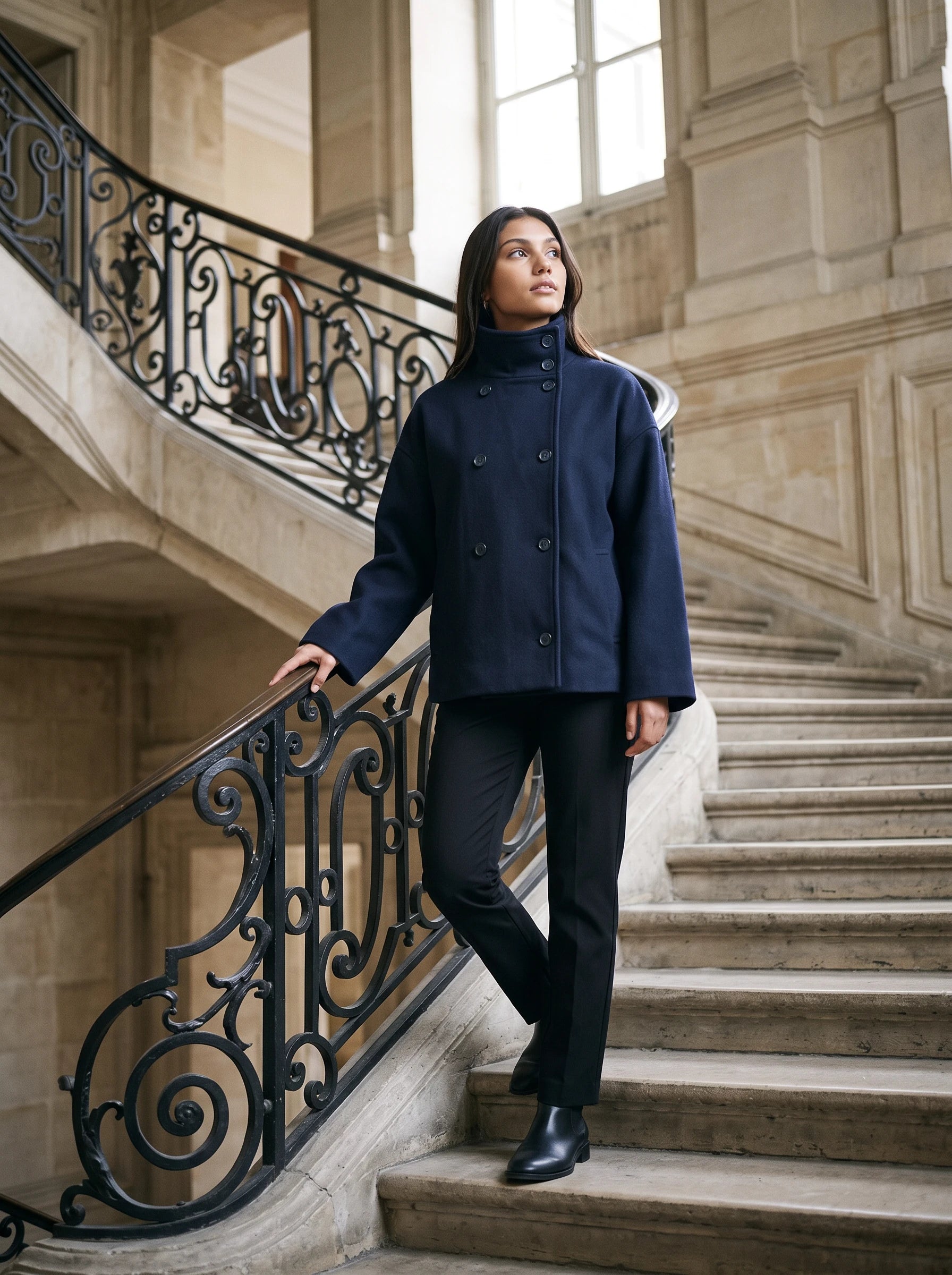 Veste en lainage bleu marine Rosalinde, portée dans un grand escalier de pierre