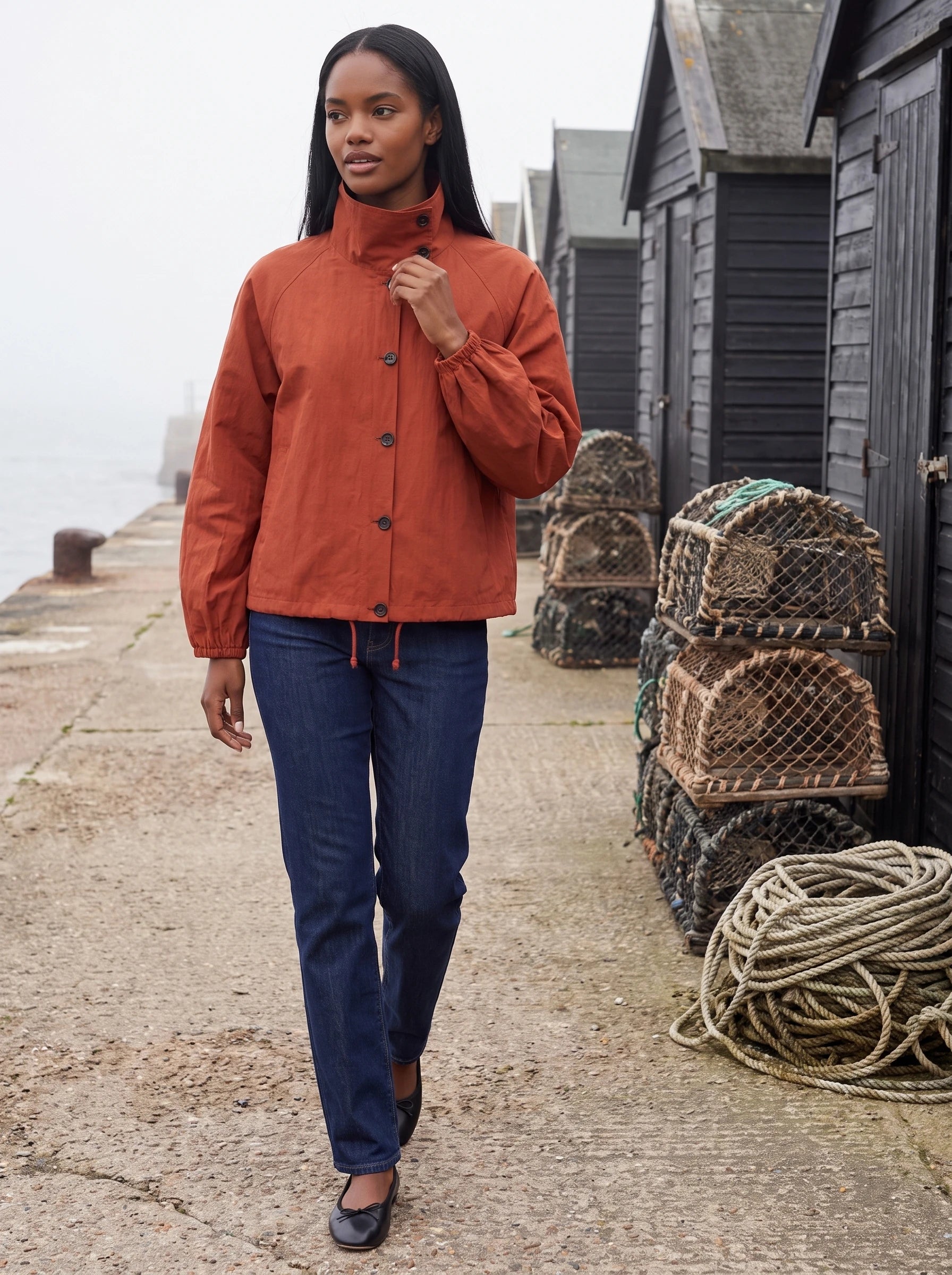 Veste légère rouge Euphrasie, portée sur une digue aux cabanes de pêcheurs
