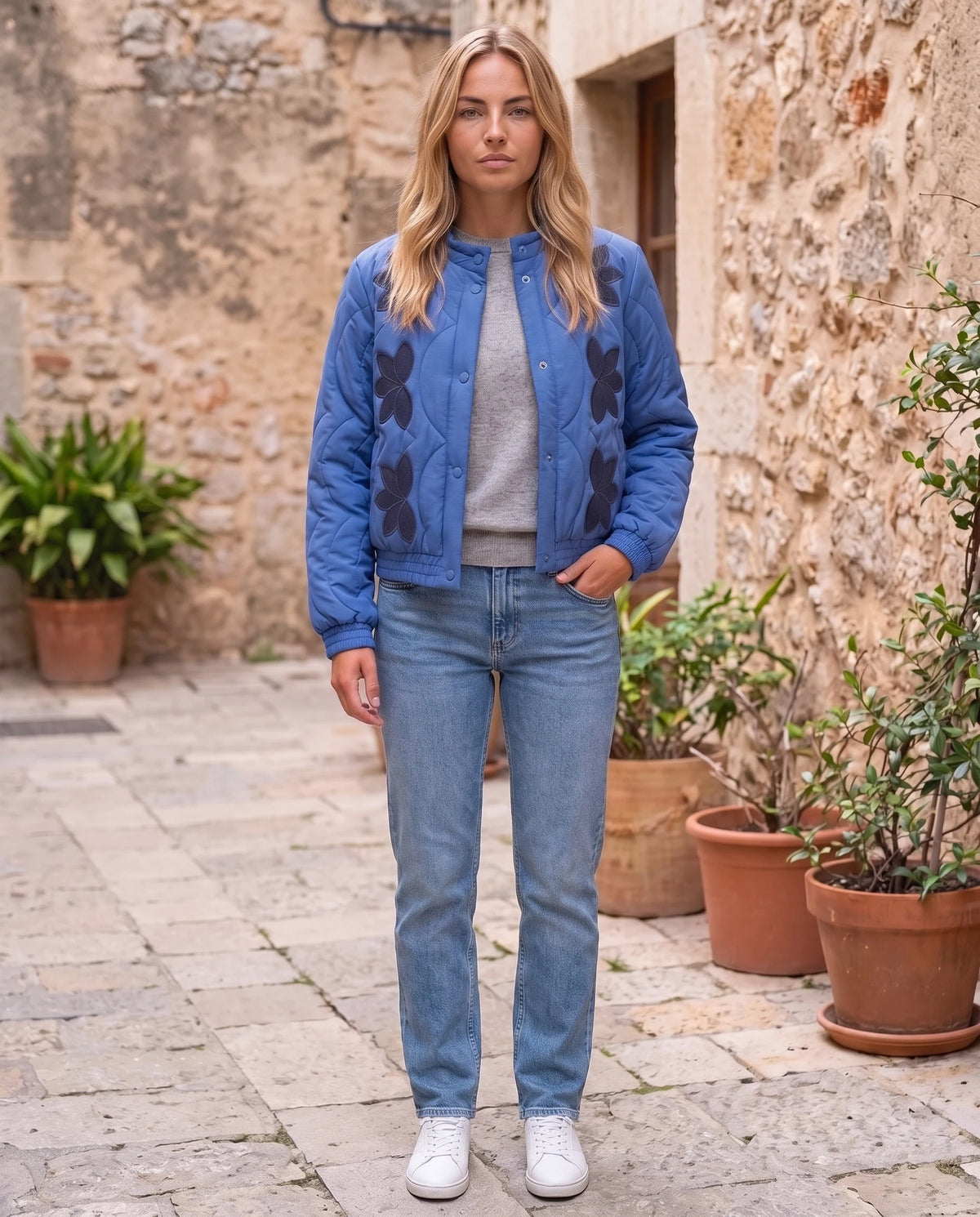 Veste matelassée col montant à pressions Julie en Bleu, portée dans une cour pavée, portée ouverte