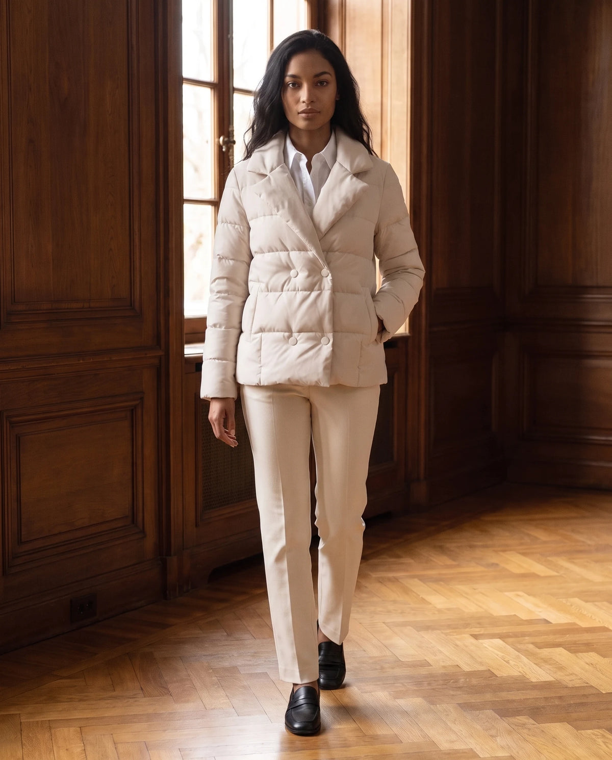 Veste matelassée courte col tailleur Agnès en Écru, portée dans un hall aux boiseries