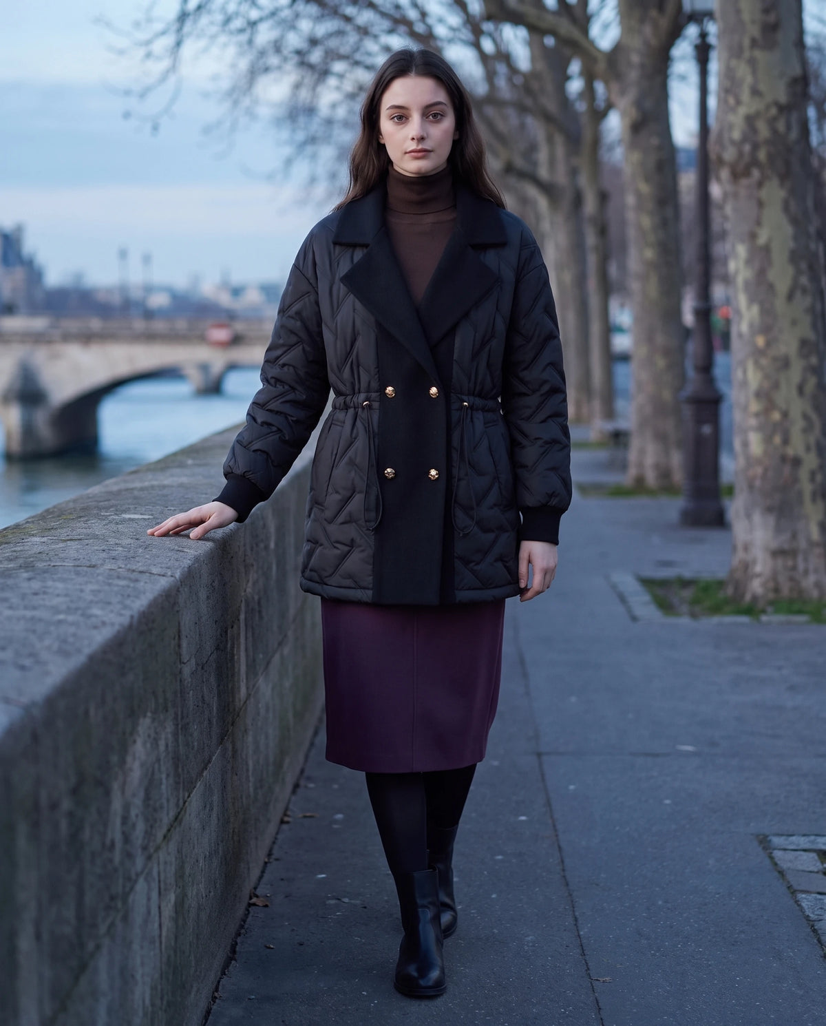 Veste matelassée mi-longue à grand col tailleur Géraldine en Noir, portée le long d'un quai de Seine