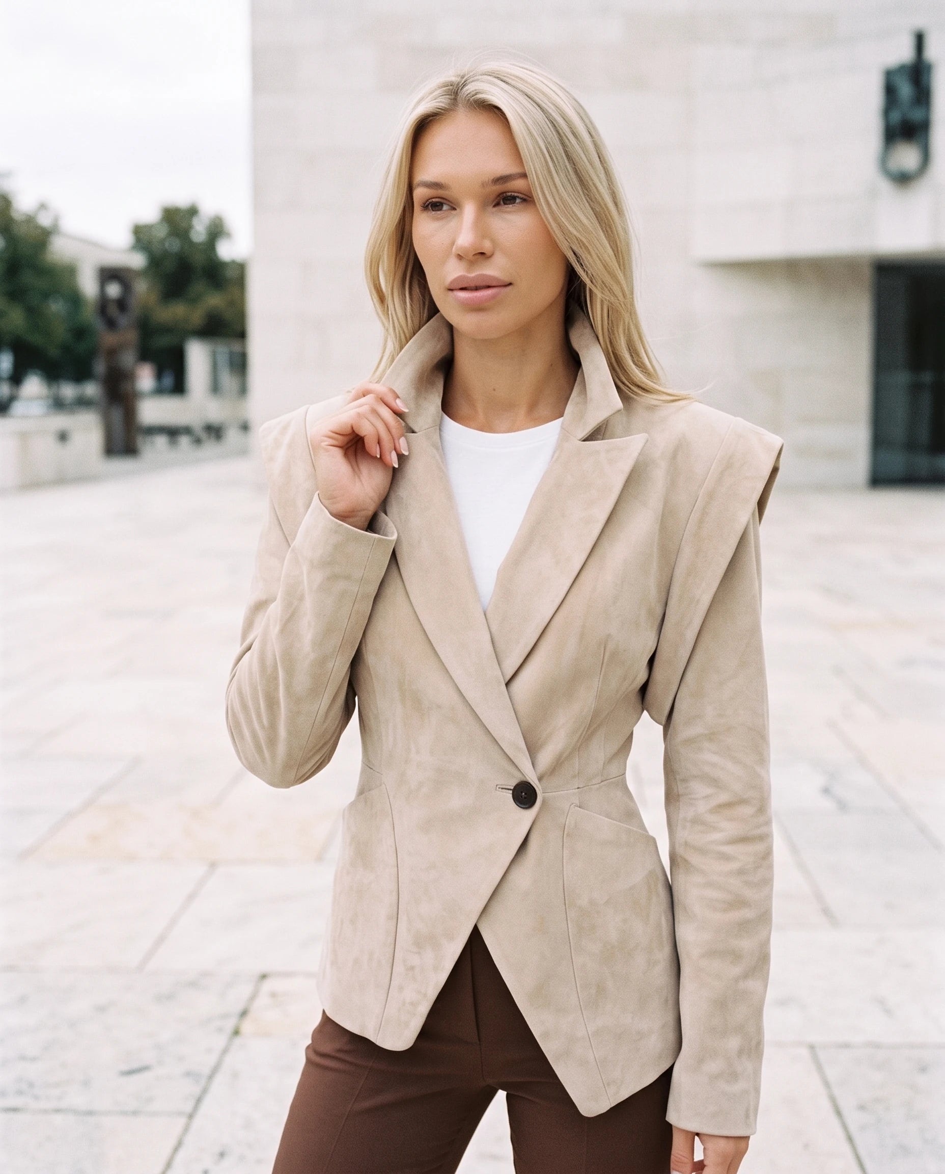 Veste en suédine cintrée beige sable Adeline, sur une esplanade claire en pierre