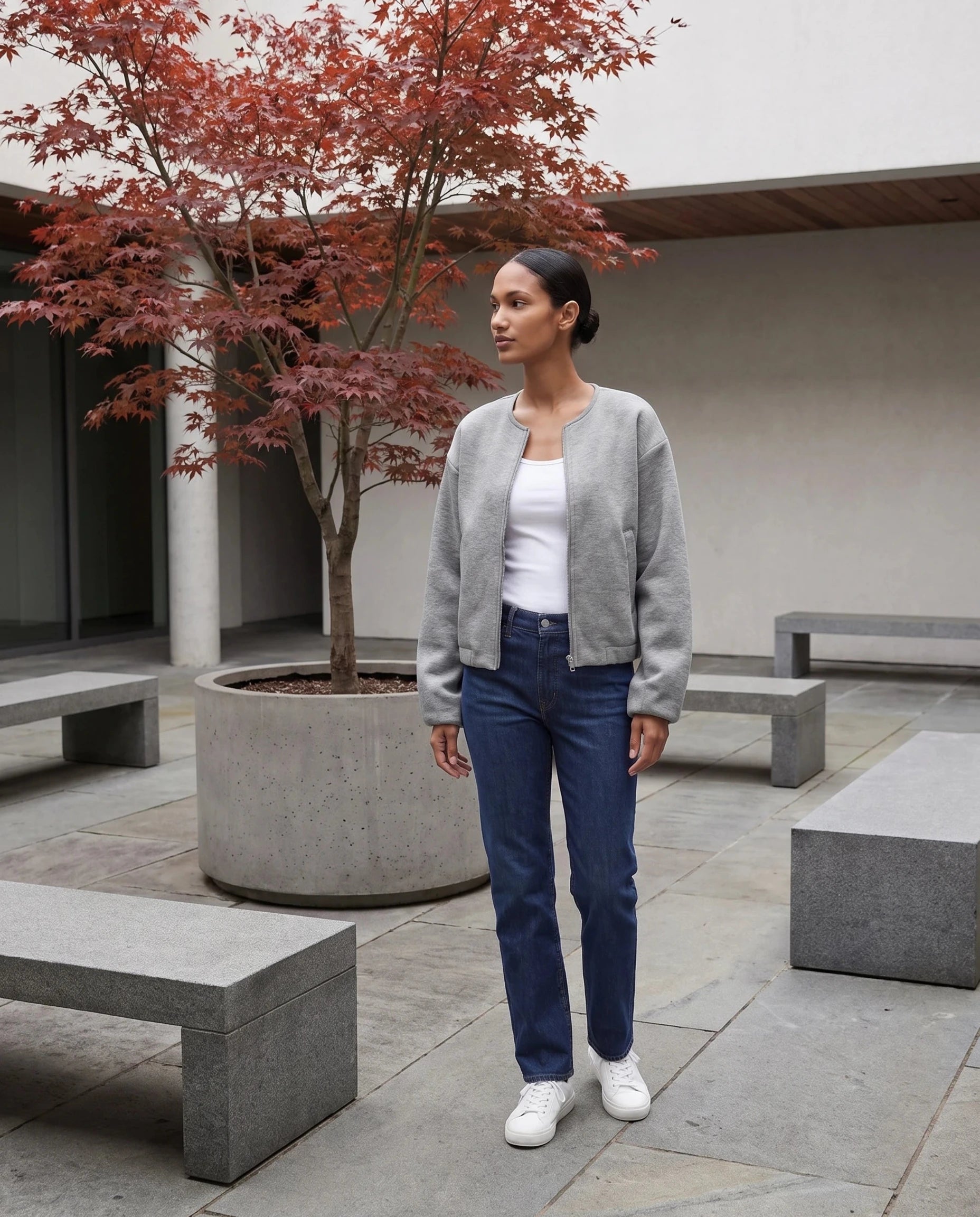 Veste zippée sans col gris chiné Germaine, portée dans une cour minérale à l'érable