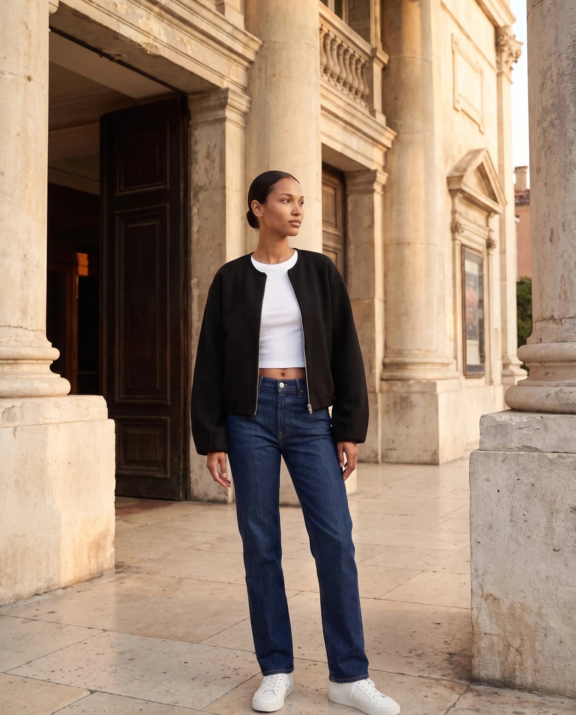 Veste zippée sans col noire Germaine, portée sur le parvis d'un théâtre ancien
