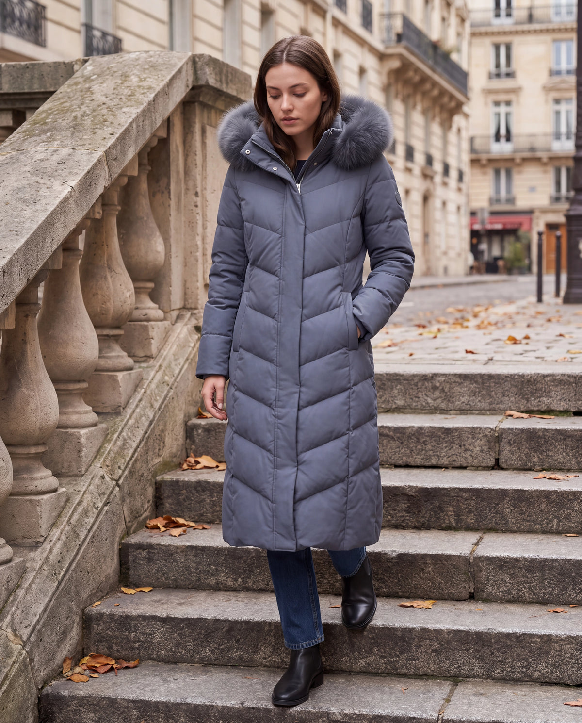 Doudoune femme Zolena — parka longue bleu ardoise à capuche fausse fourrure sur un escalier en pierre