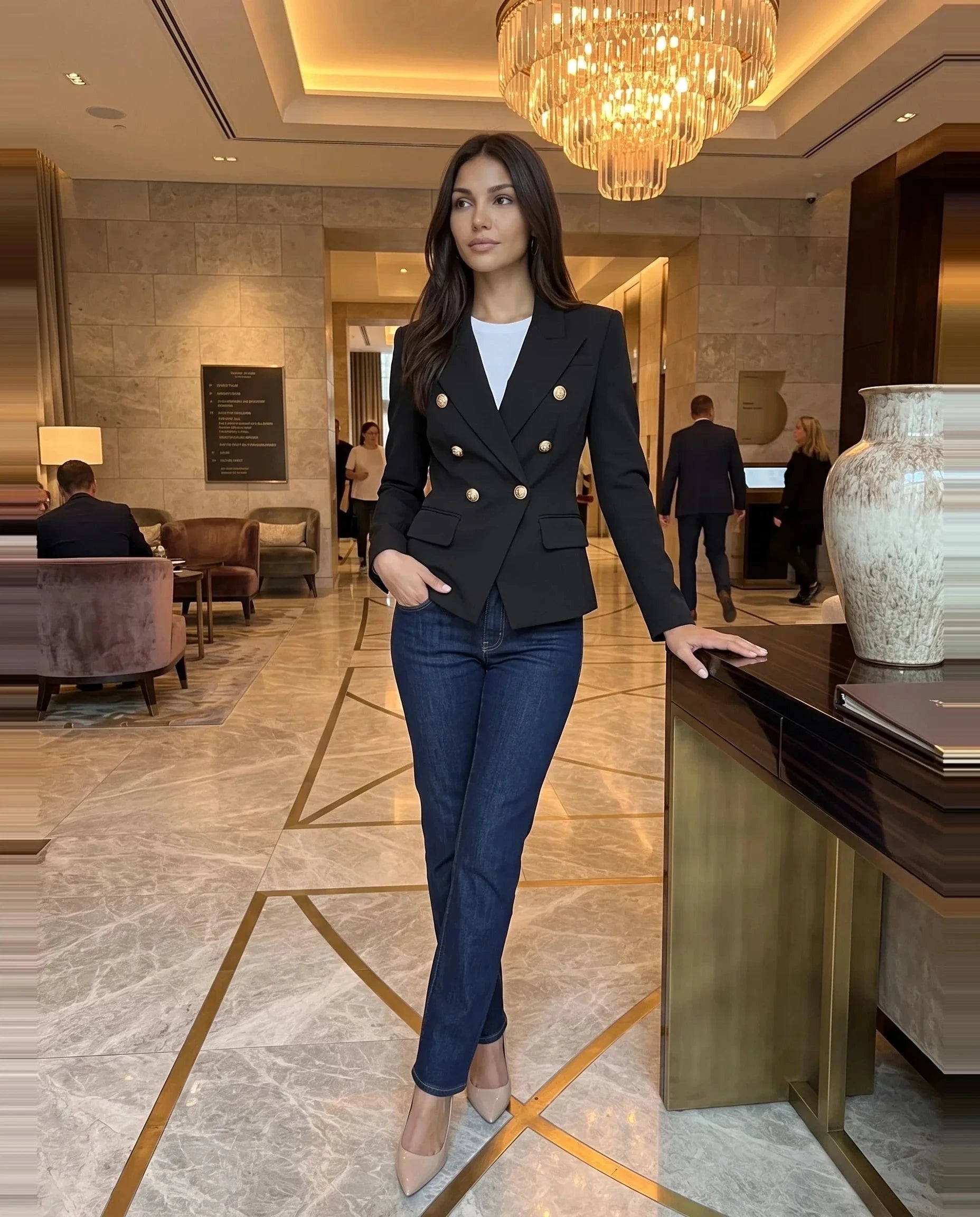 Blazer noir à boutons lion Thaïs, porté dans un hall d'hôtel en marbre