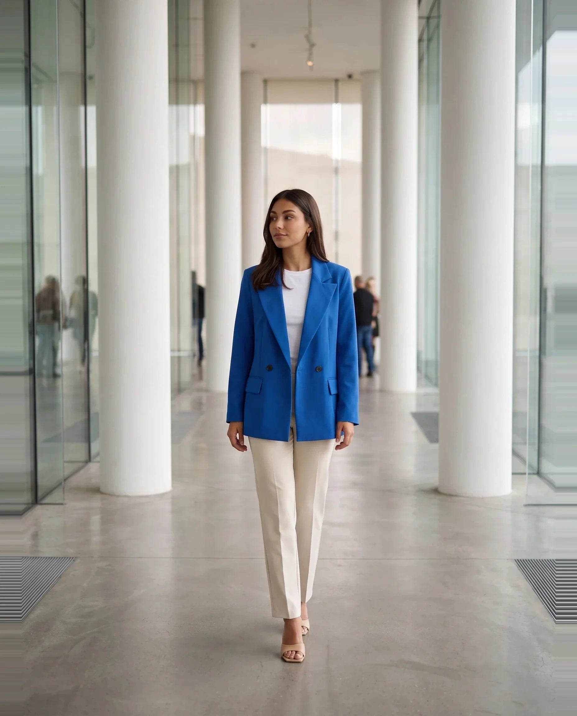 Blazer bleu roi Cosima, porté dans un hall de musée contemporain à colonnes