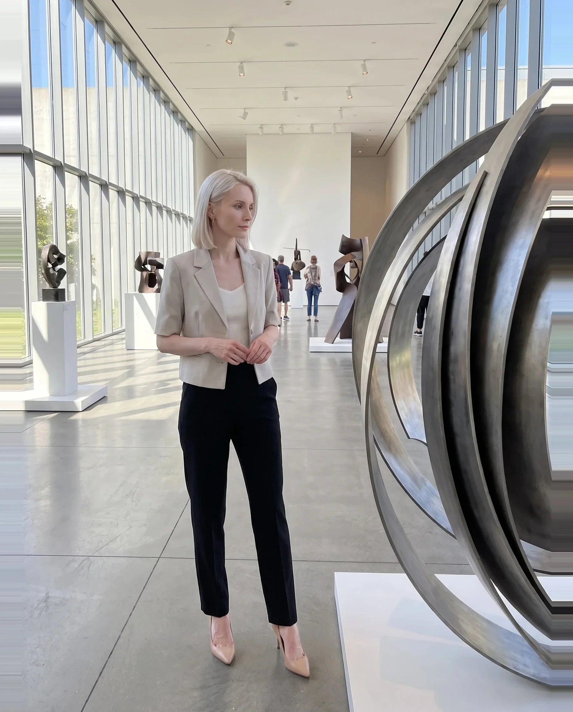 Blazer court grège Violaine, porté dans l'atrium lumineux d'un musée