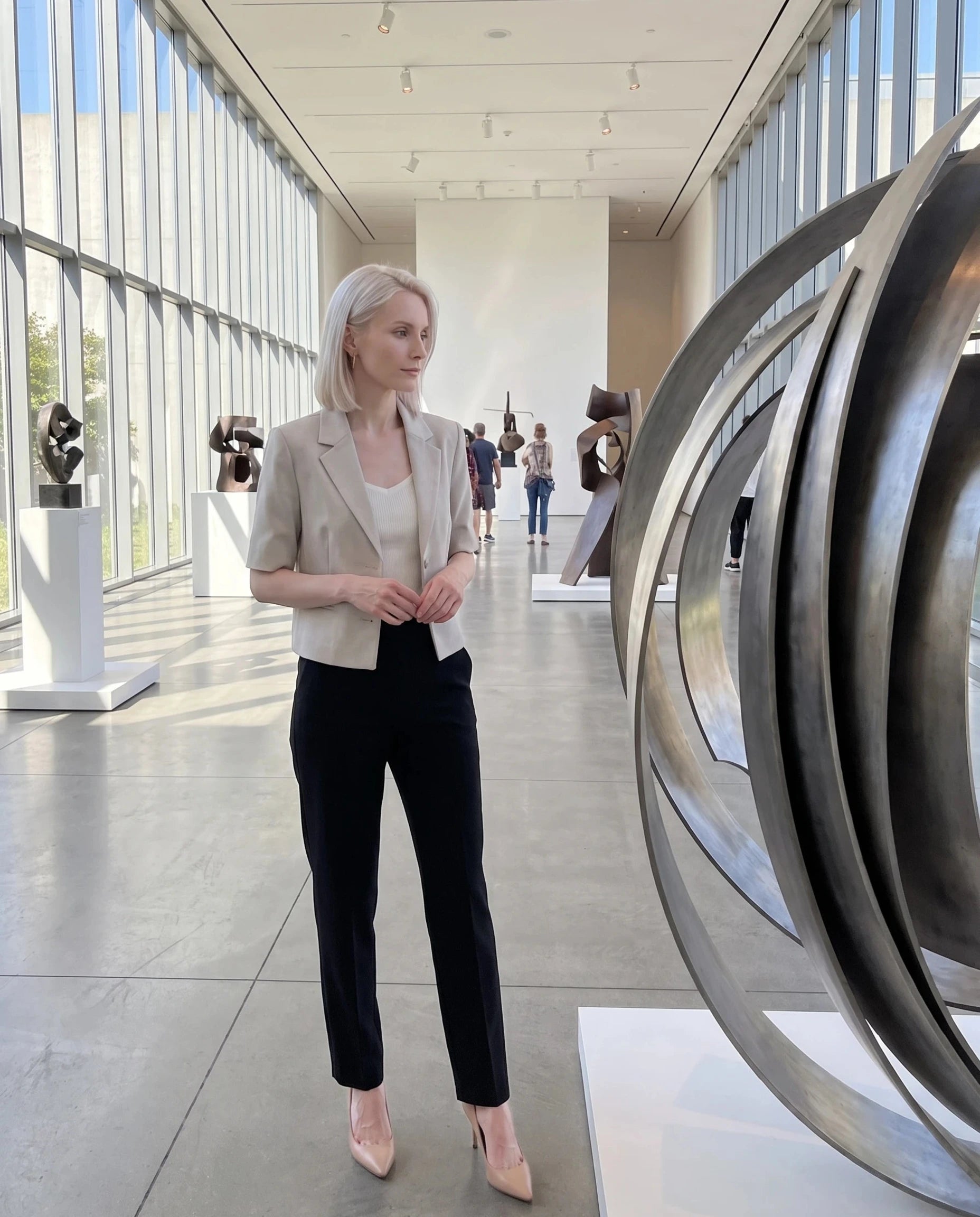 Blazer court grège Violaine, porté dans l'atrium lumineux d'un musée