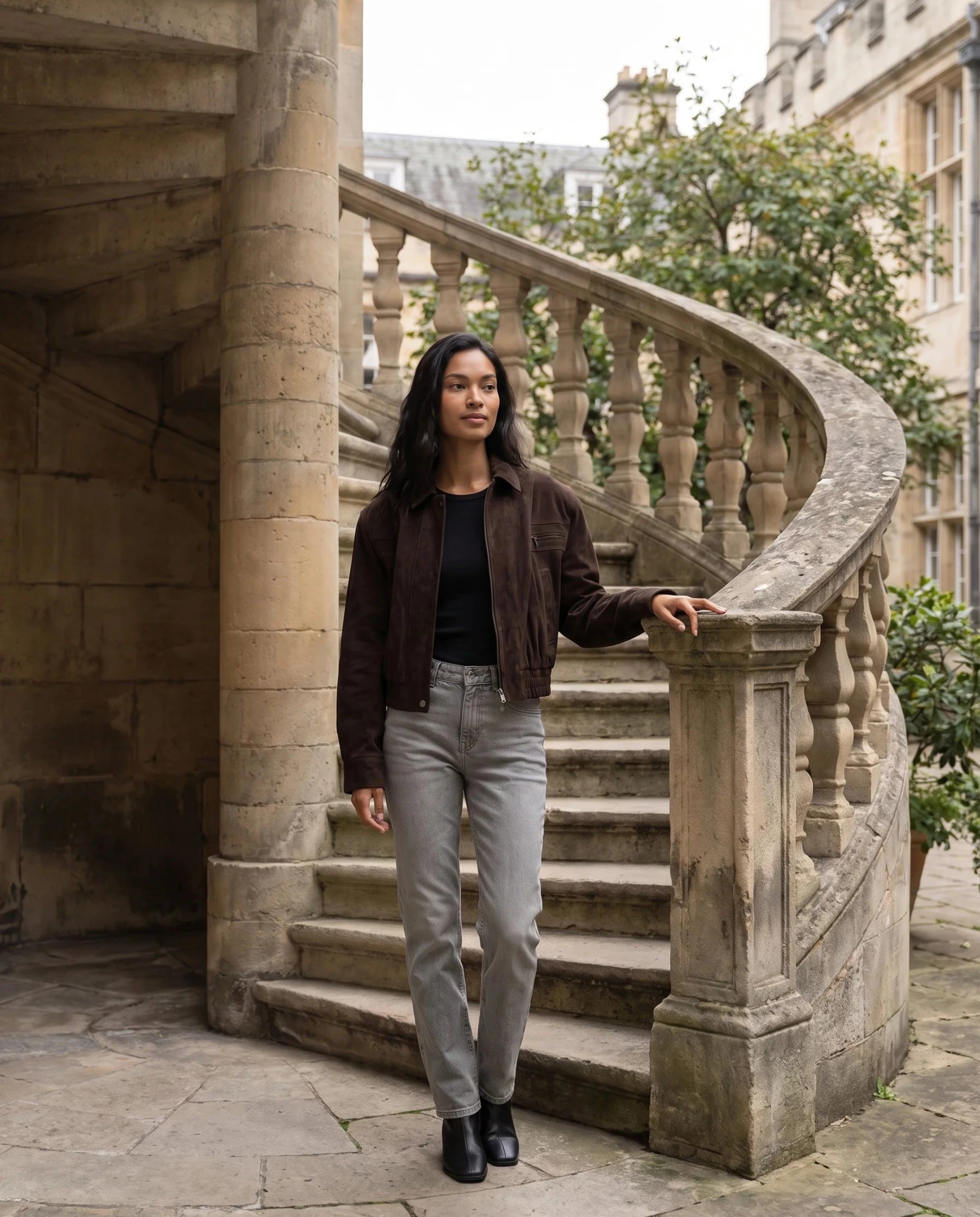 Bomber crop en suédine brun Fabienne, porté près d'un escalier de pierre en colimaçon