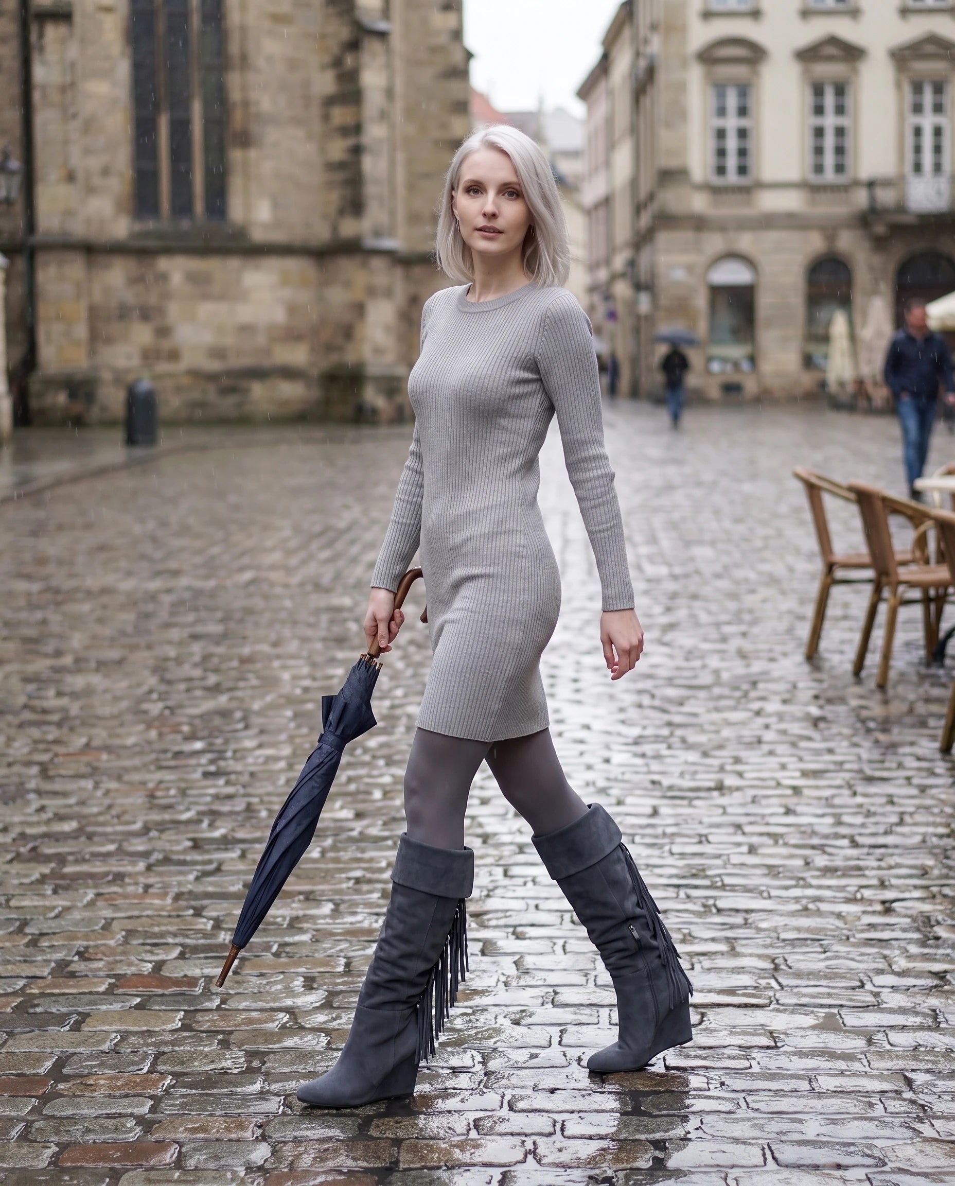 Bottes hautes à franges à talon compensé Alexandrine — Gris Ardoise, portées sur une place pavée sous la pluie