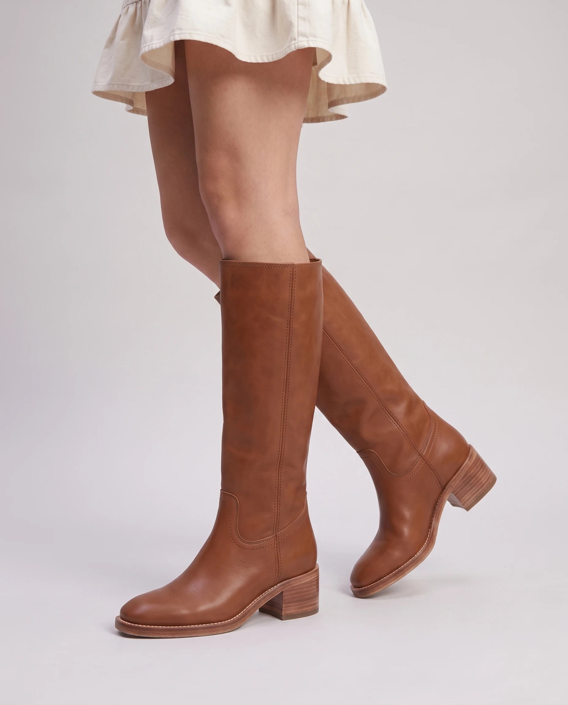 Bottes hautes à talon empilé effet cuir Nicolette — Cognac, portées en plan rapproché avec une robe courte