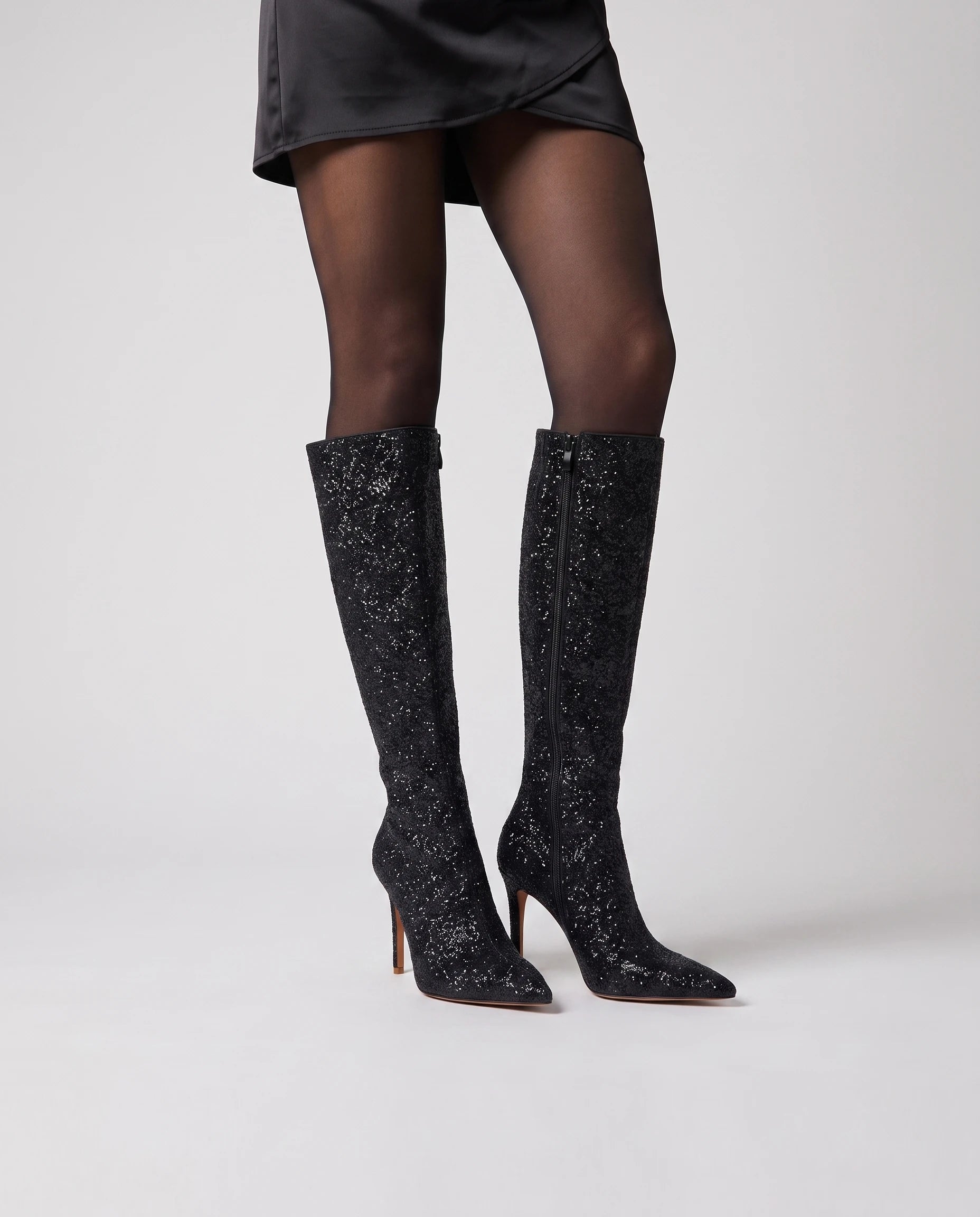 Bottes hautes à paillettes à talon aiguille Amarante — Noir, portées en plan rapproché avec des collants opaques