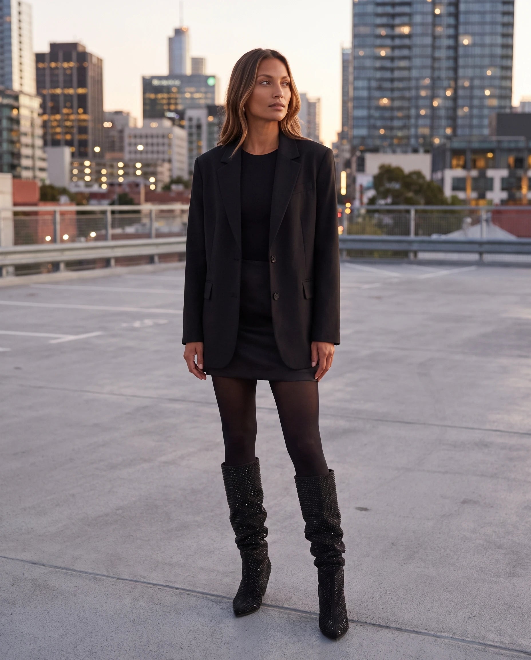 Bottes hautes slouchy à strass Odalie — Noir, portées sur un toit-terrasse de parking au crépuscule