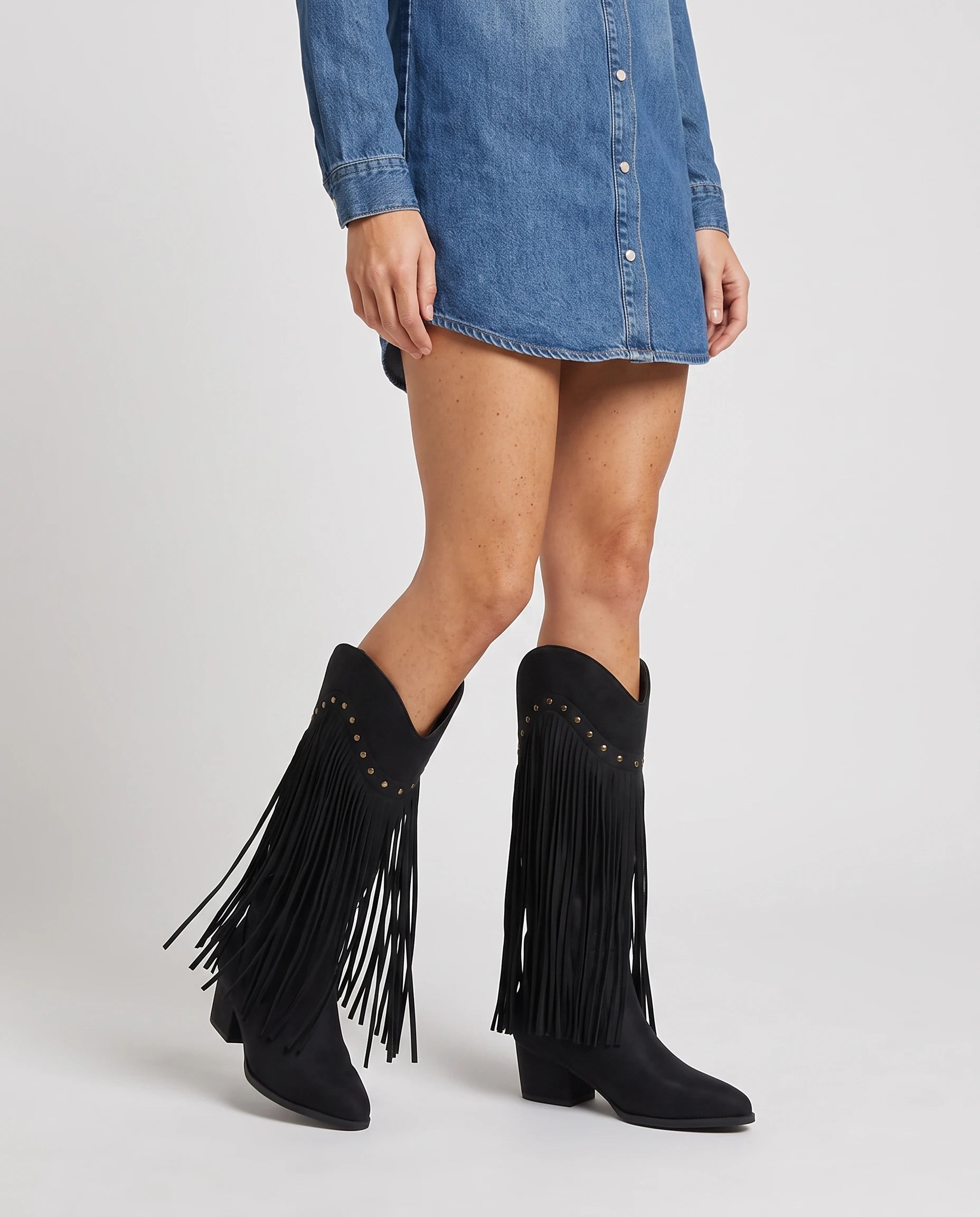 Bottes hautes western à franges cloutées Florentine — Noir, portées en plan rapproché avec une robe en jean