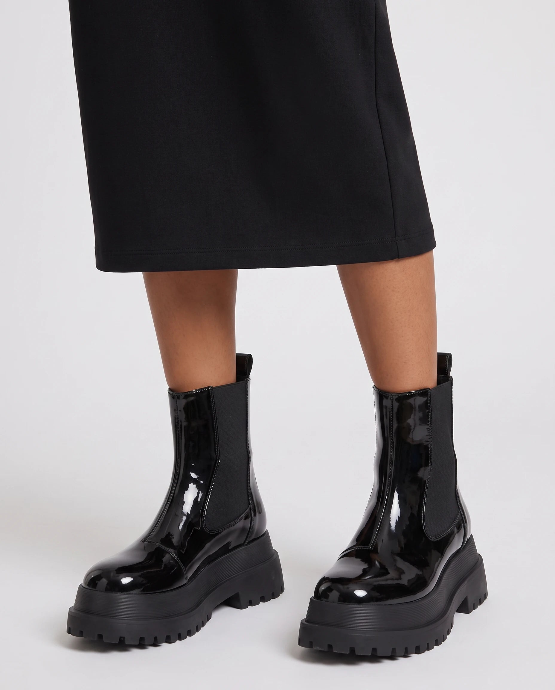 Bottines chelsea vernies à plateforme Gaëlle — Noir Verni, portées en plan rapproché avec une jupe midi