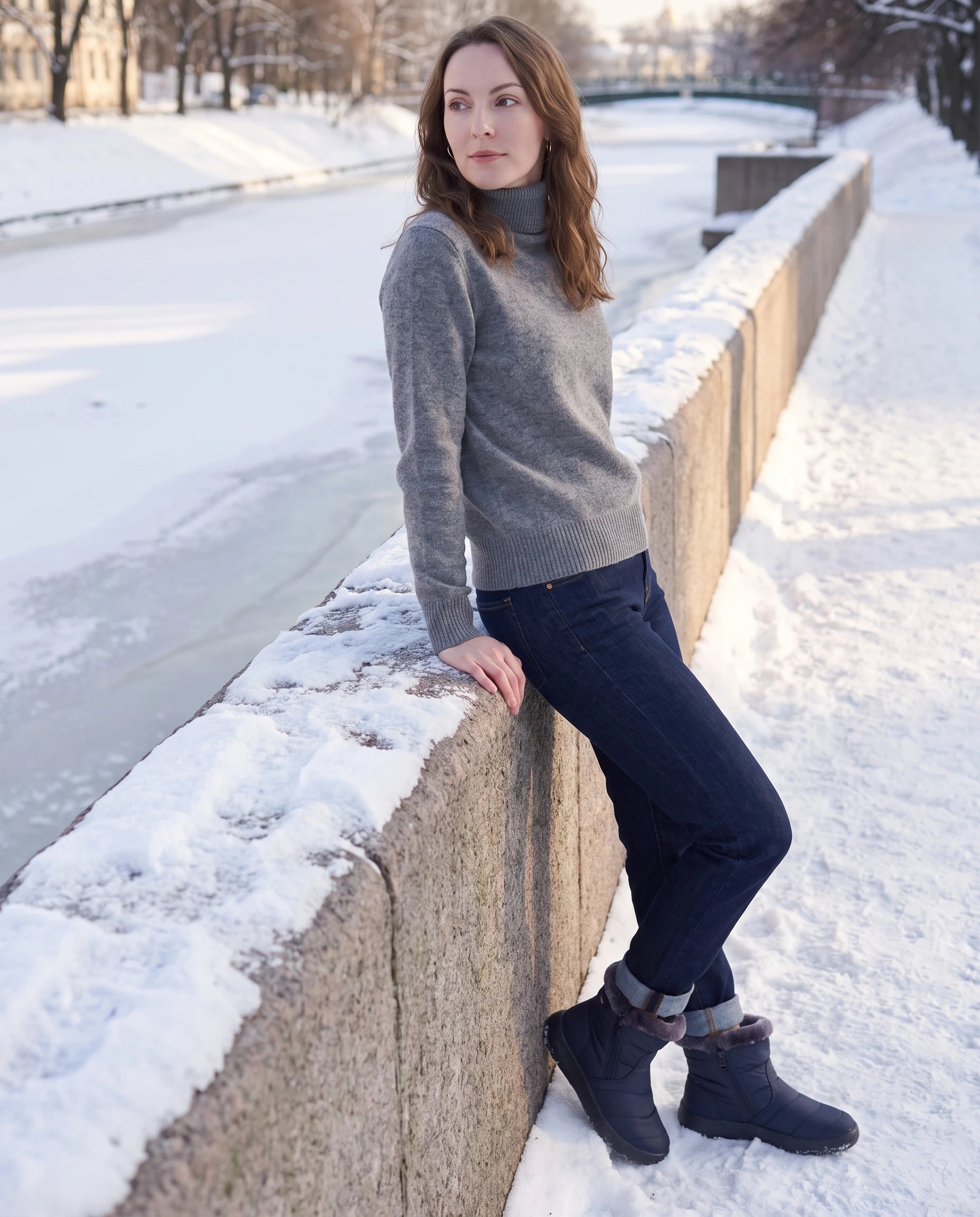 Bottines de neige fourrées Noëlle — Bleu Marine, portées sur un pont de pierre au-dessus d'un canal gelé