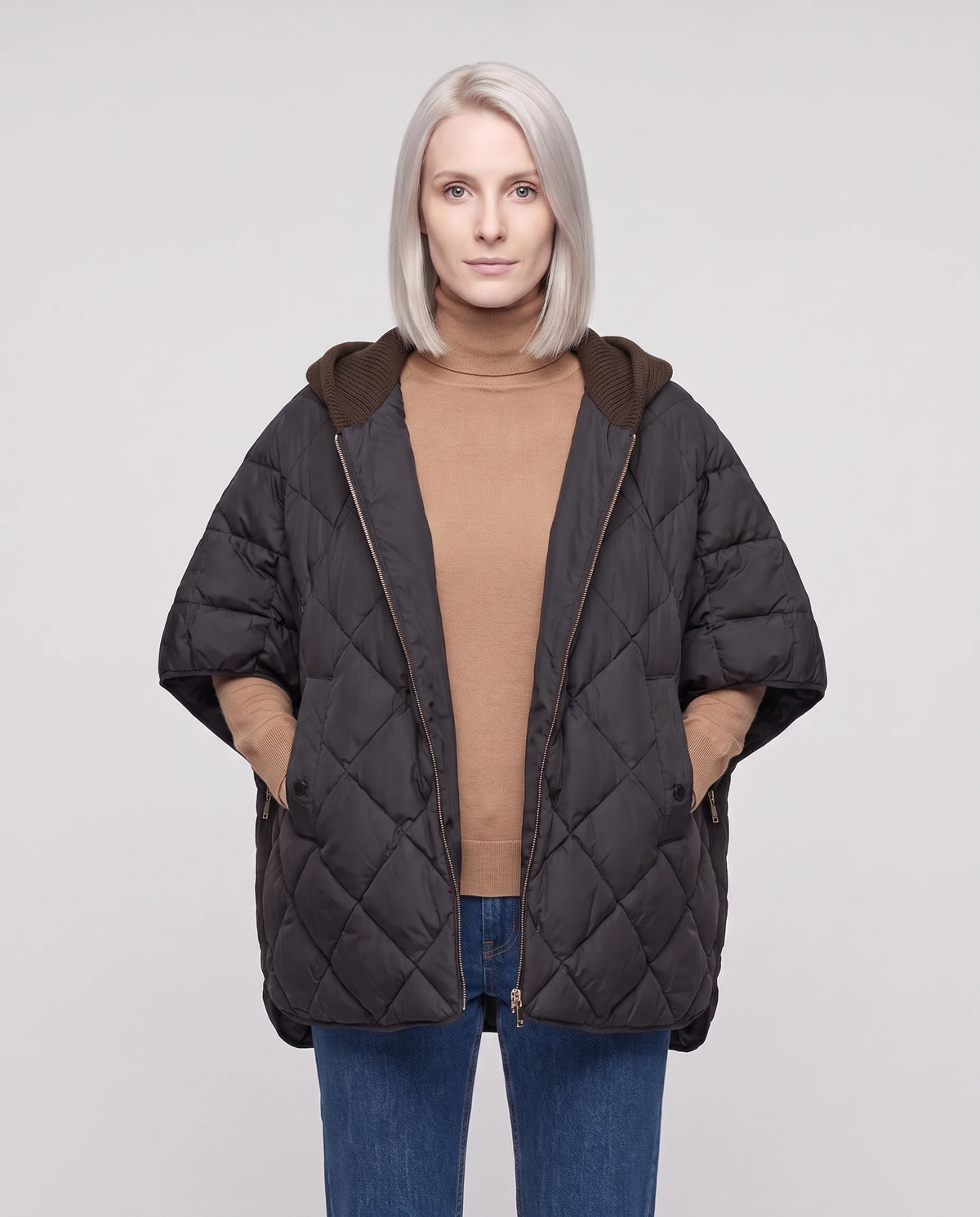 Cape matelassée à capuche tricot Stella en Noir, portée ouverte sur un col roulé camel, plan rapproché