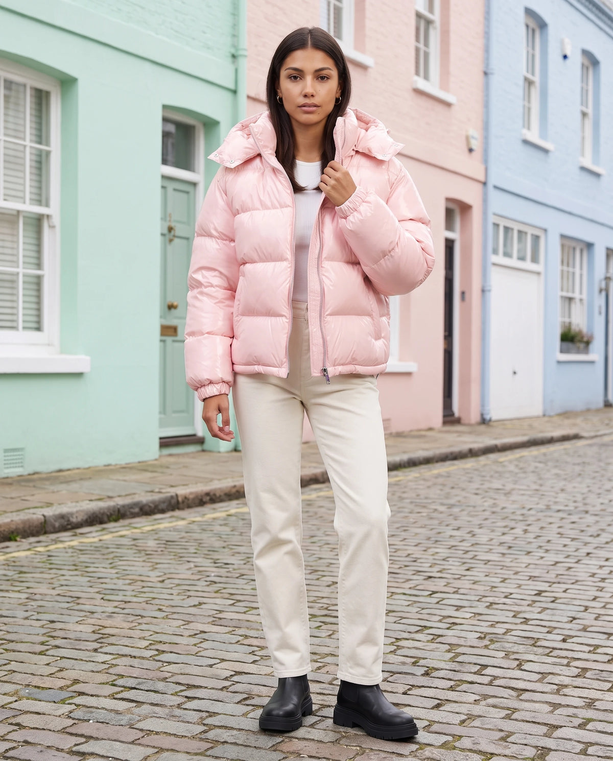 Doudoune brillante Tessa en Rose, portée dans une rue de maisons pastel