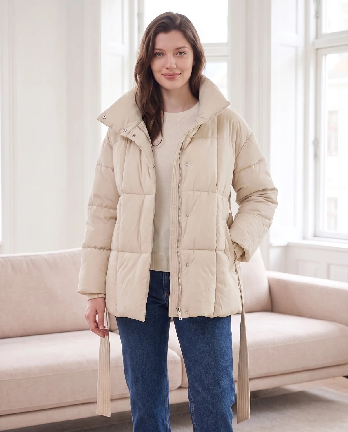 Steppjacke mit Bindegürtel und Stehkragen Lou in Ecru, getragen in einem hellen Wohnzimmer, Gürtel lose