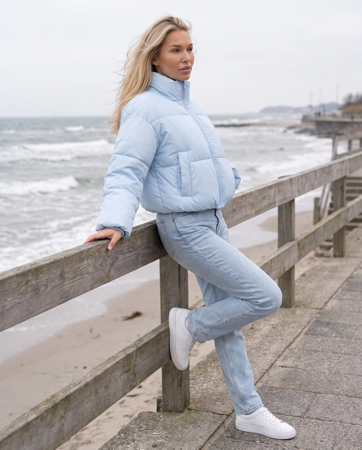Kurze Steppjacke Odeline in Hellblau, getragen auf einer Strandpromenade