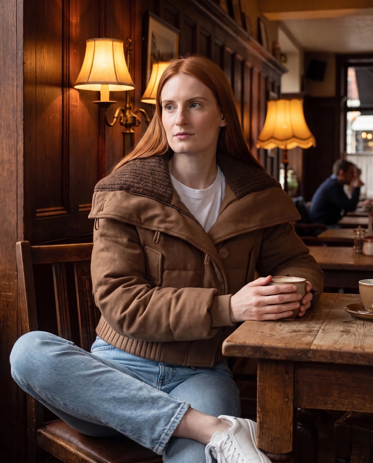 Doudoune courte à col tricot boutonnée Livie en Marron, portée dans un café aux boiseries