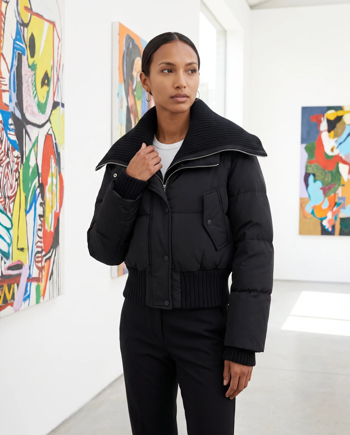 Doudoune courte à col tricot Nella en Noir, portée dans une galerie d'art