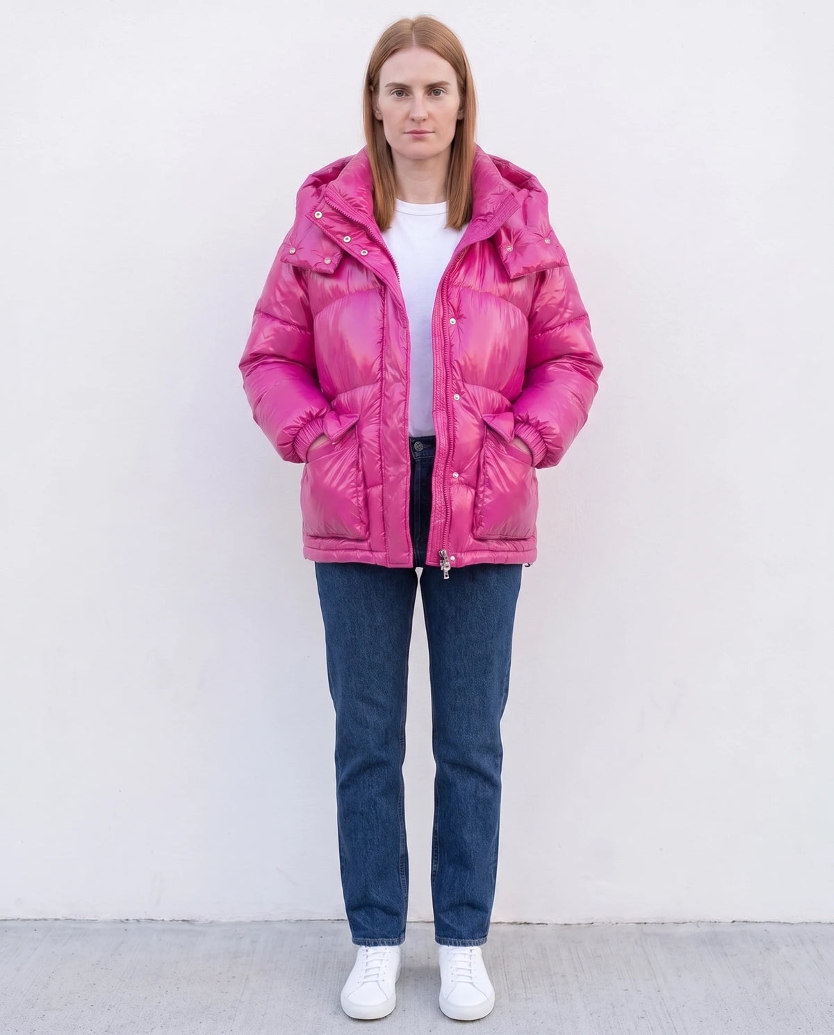 Doudoune courte brillante à capuche et poches plaquées Saskia en Fuchsia, portée devant un mur blanc lisse