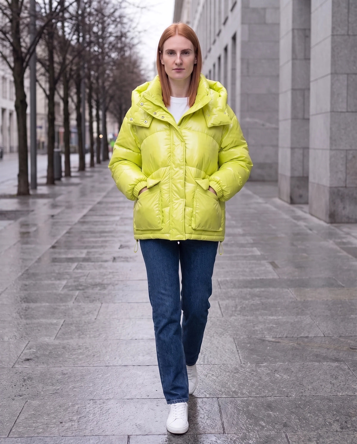 Doudoune courte brillante à capuche et poches plaquées Saskia en Jaune Citron, portée sur un trottoir de ville