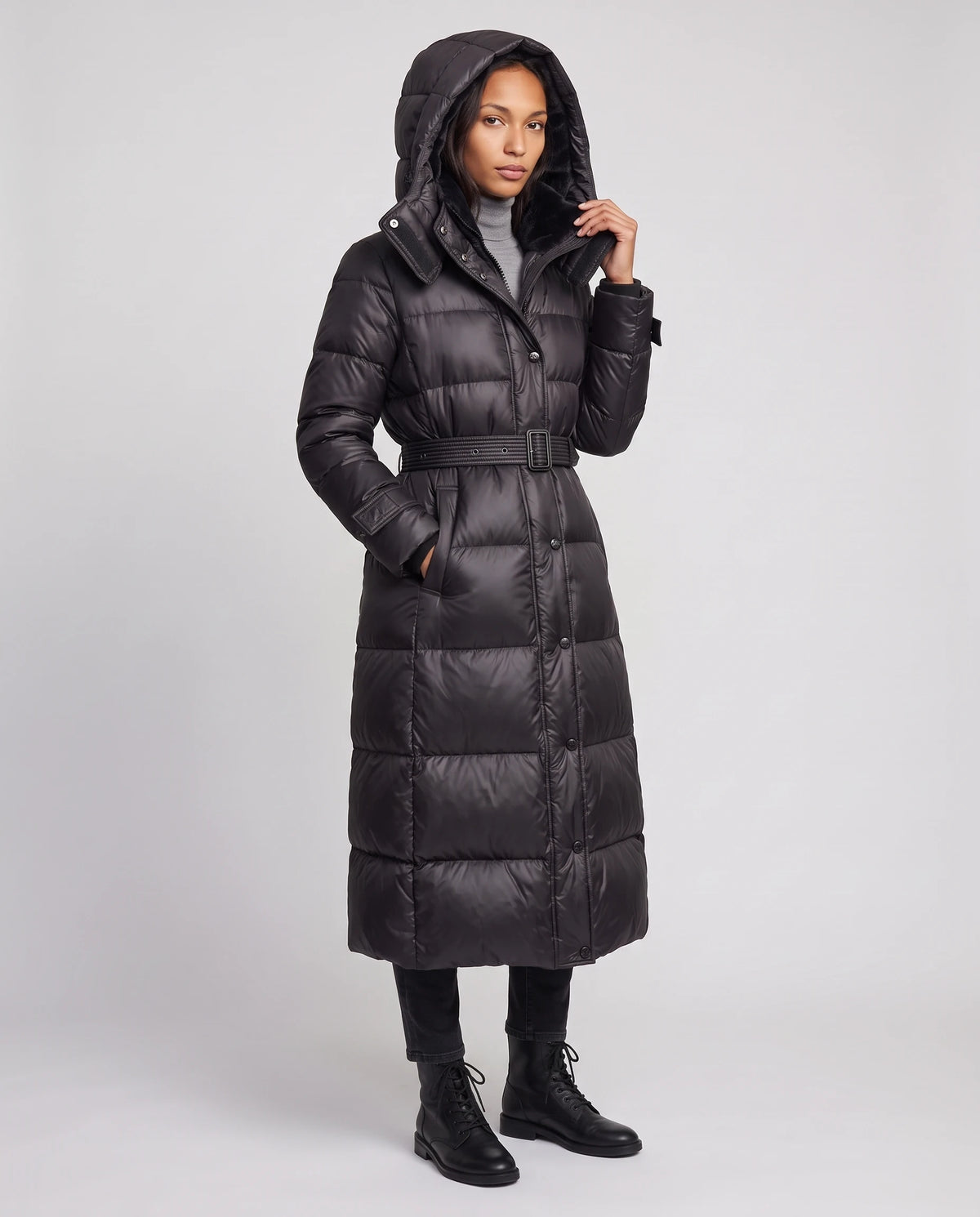 Doudoune extra-longue brillante à capuche et ceinture à boucle Carole en Noir, vue de trois quarts, capuche relevée