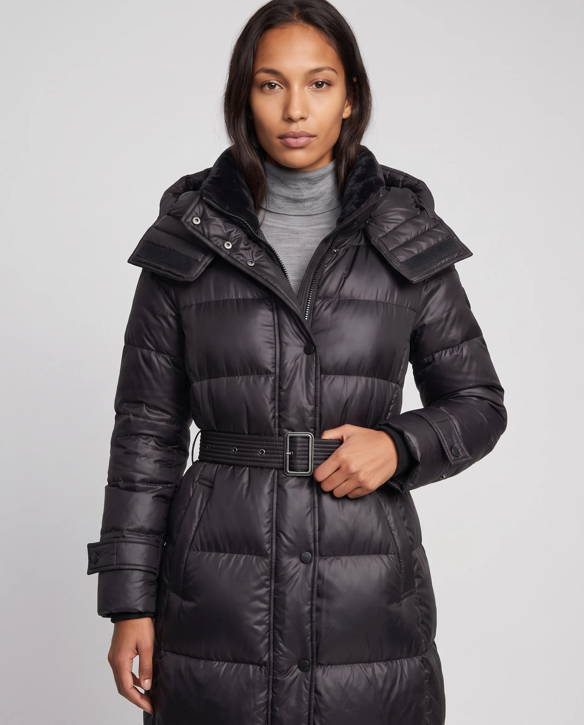 Extralange glänzende Steppjacke mit Kapuze und Schnallengürtel Carole in Schwarz, Nahaufnahme, Stehkragen, Druckknöpfe, Schnalle und Ärmelriegel