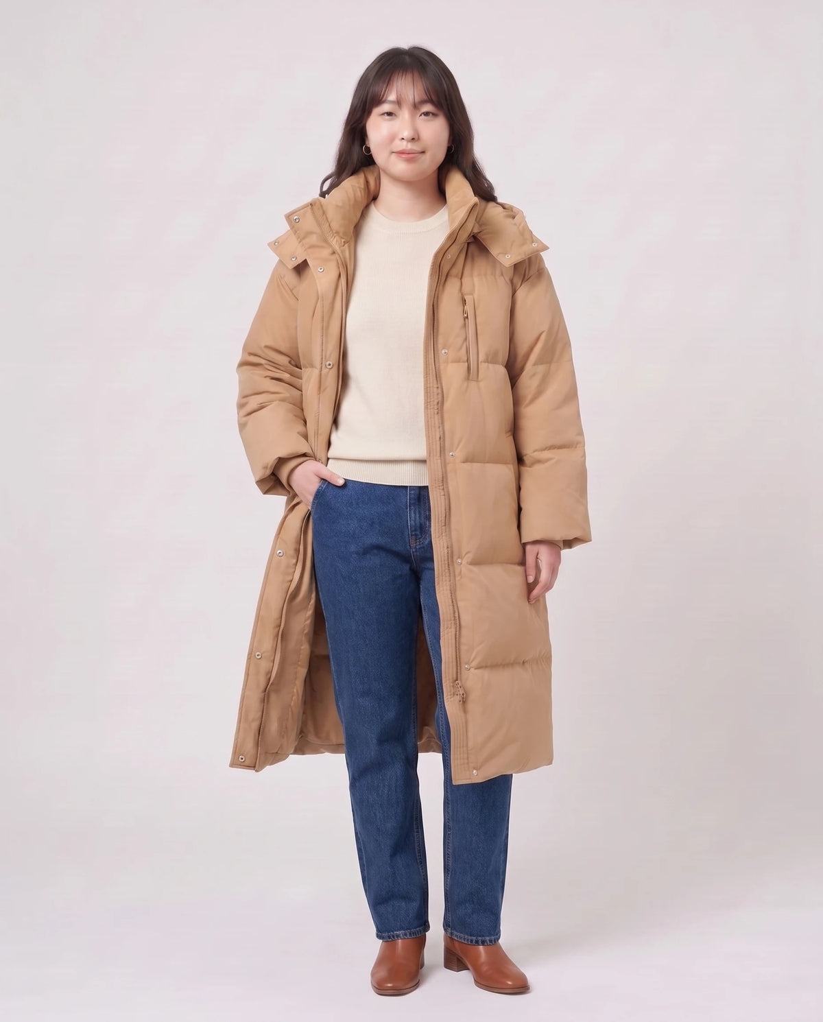 Langer Oversize-Steppmantel mit Kapuze Enora in Camel, offen getragen über ecrufarbenem Pullover, Futter sichtbar
