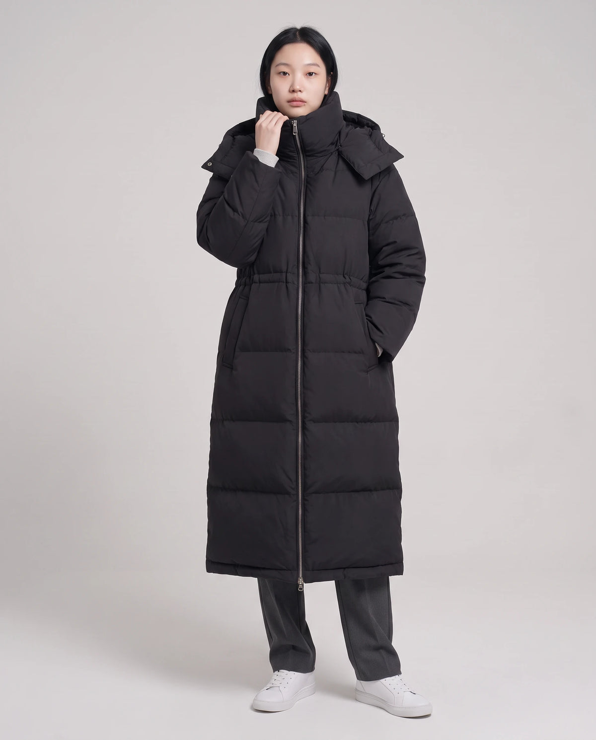 Langer Oversize-Steppmantel mit Stehkragen und Kapuze Lucille in Schwarz, Vorderansicht in ganzer Länge, bis zum Kragen geschlossen, Kordel gezogen, Kapuze abgelegt