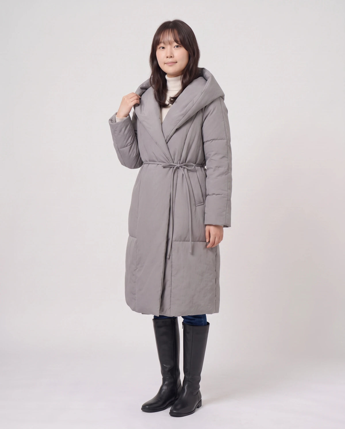 Doudoune longue portefeuille à capuche oversize Aurélia en Gris, vue de trois quarts, capuche baissée, main au col