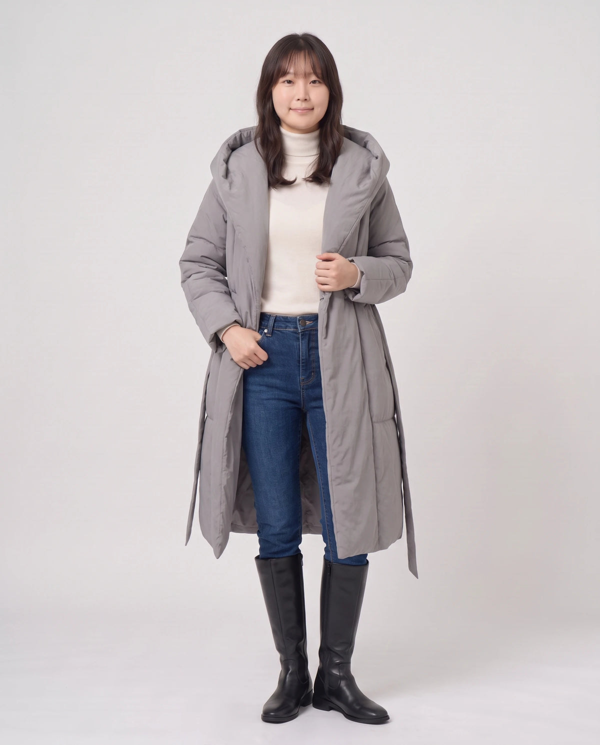Doudoune longue portefeuille à capuche oversize Aurélia en Gris, portée ouverte sur un col roulé crème, ceinture libre