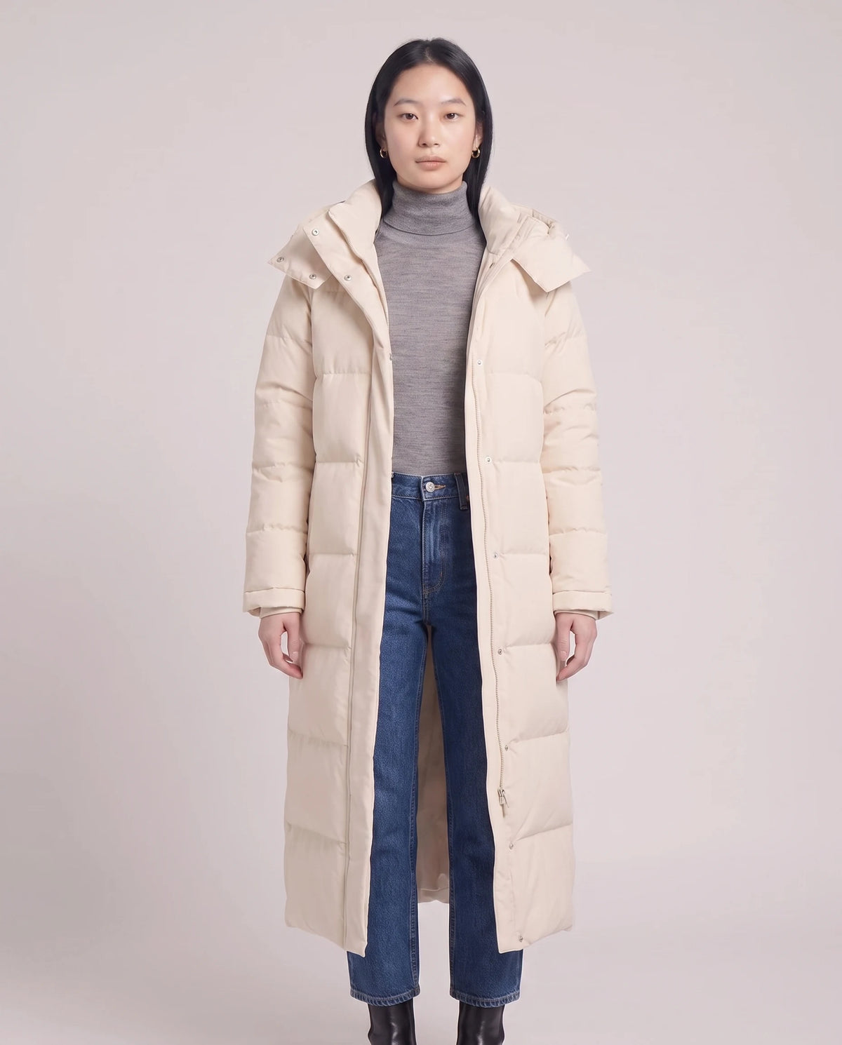 Extralanger Steppmantel mit Kapuze Clara in Weiss, offen getragen über grau meliertem Rollkragenpullover, Nahaufnahme