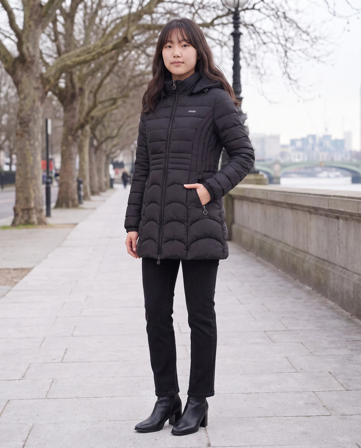 Doudoune mi-longue cintrée à capuche Angeline noire, quai bordé d'arbres en hiver
