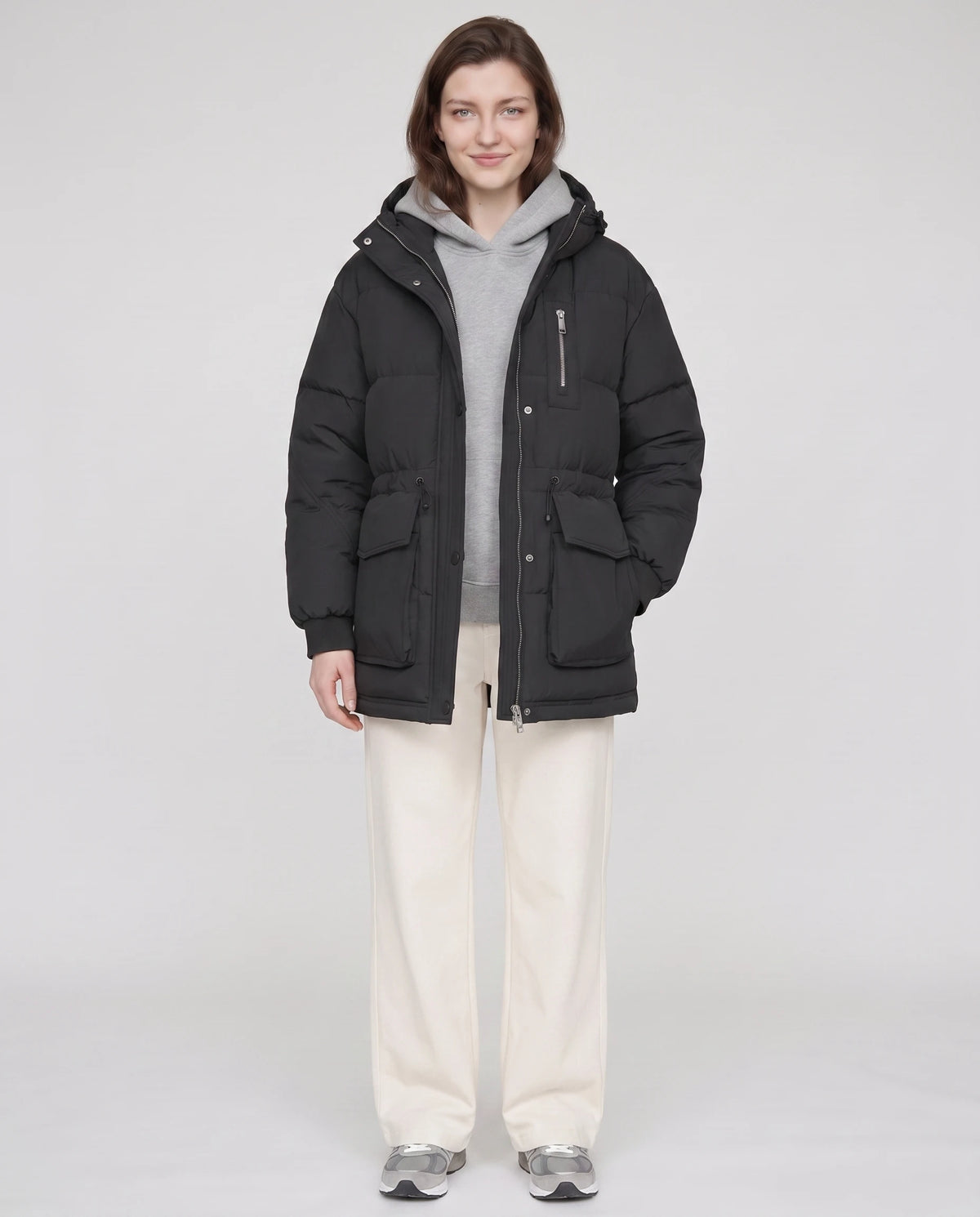 Mittellange Parka-Steppjacke mit Pattentaschen Muriel in Schwarz, offen getragen über grauem Hoodie, Druckknöpfe offen