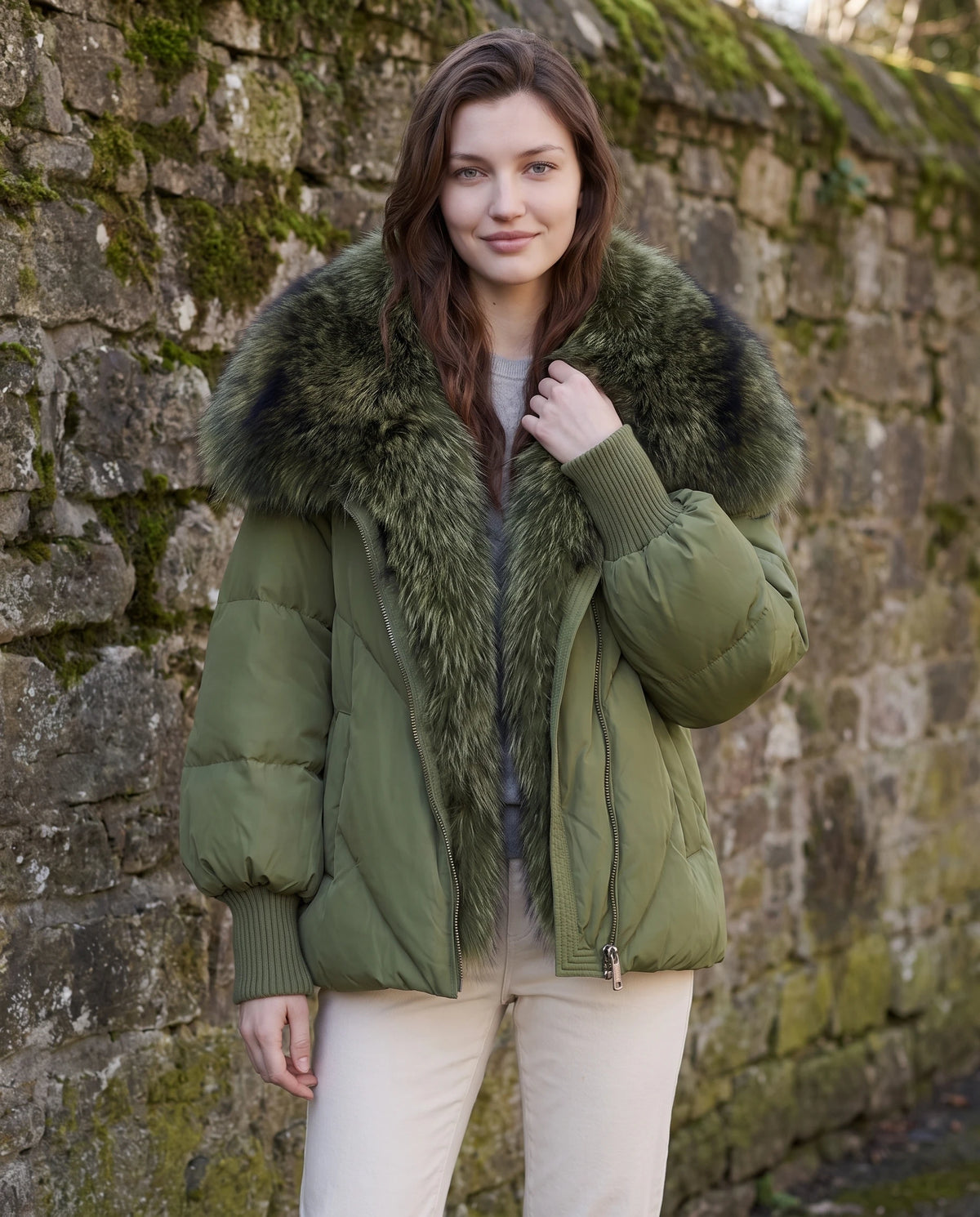 Doudoune oversize à col châle fausse fourrure Sabrina en Vert Olive, portée devant un mur de pierre moussue