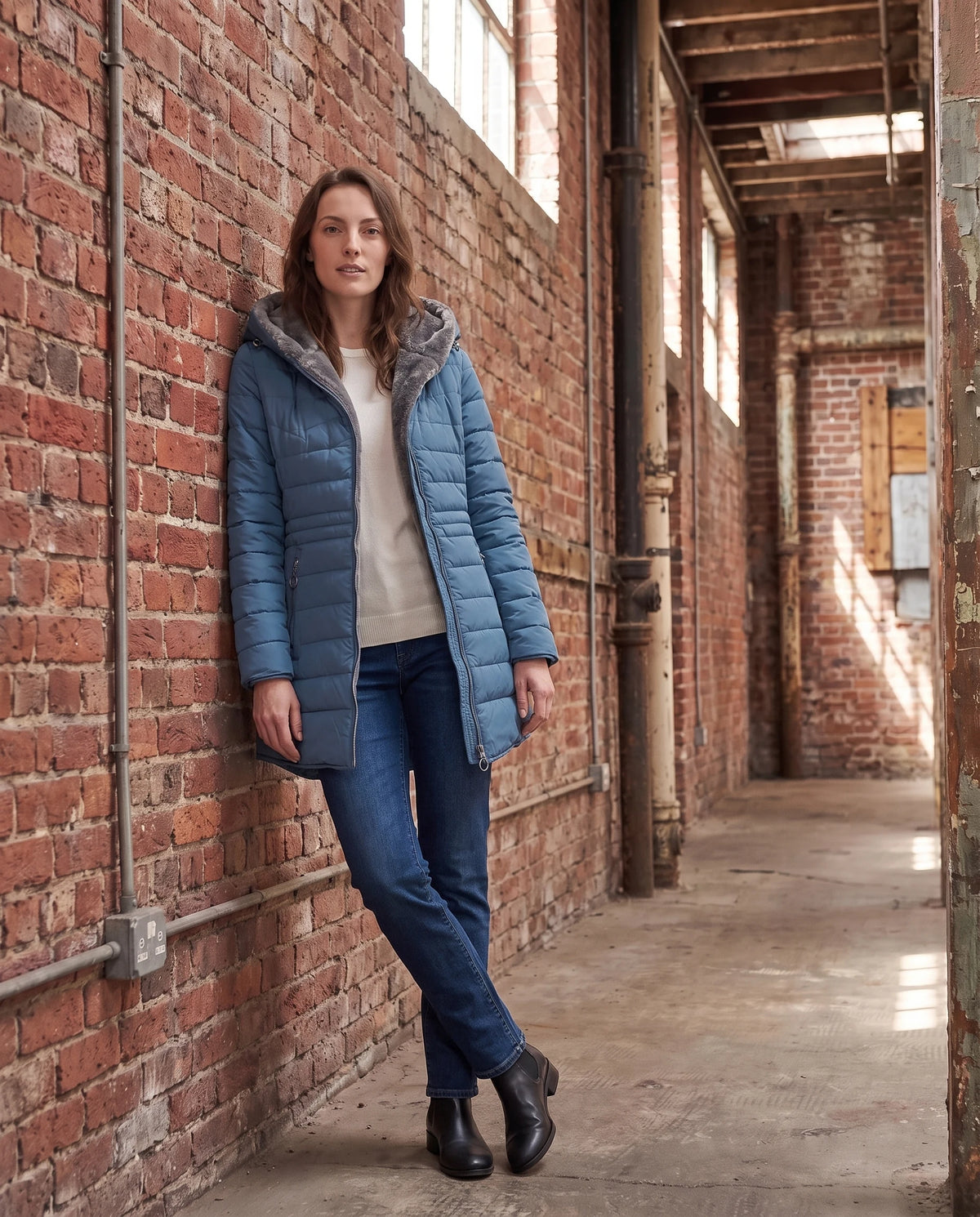 Doudoune doublée polaire Aubine en Bleu Denim, portée dans un passage industriel en brique