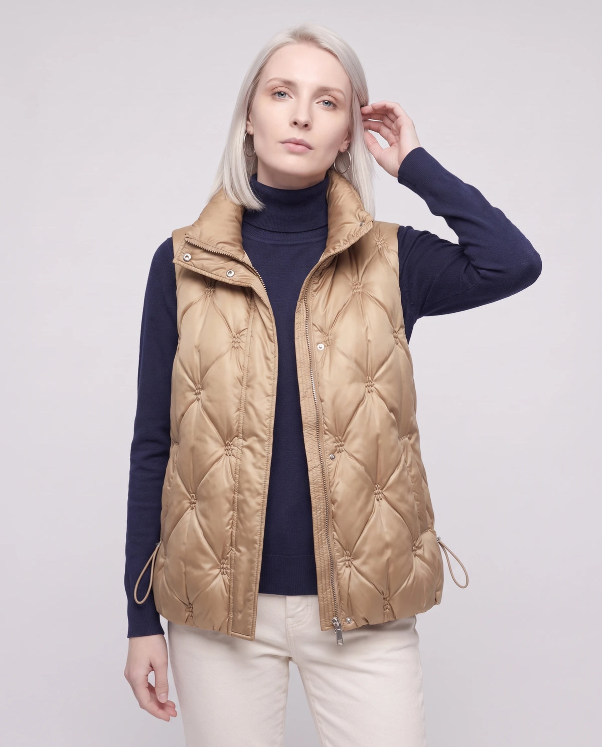 Doudoune sans manches capitonnée en satin Marielle, coloris Beige Doré, plan rapproché de face, fermée, main qui replace une mèche