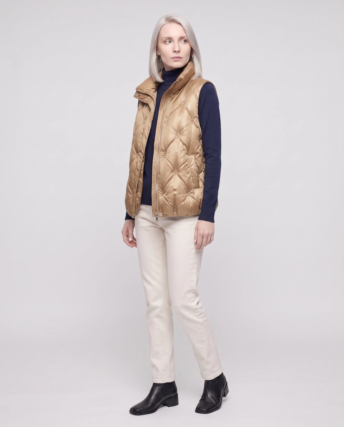 Doudoune sans manches capitonnée en satin Marielle, coloris Beige Doré, plein pied de trois quarts sur col roulé marine et jean écru
