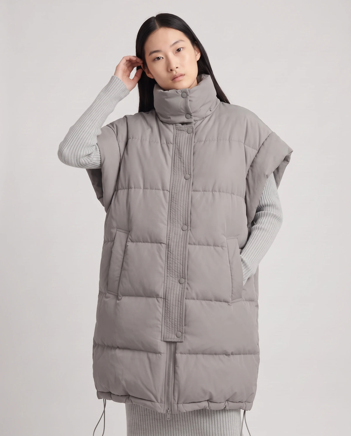 Doudoune sans manches oversize à grand col et patte plissée Perline en Gris, plan rapproché, main qui replace une mèche