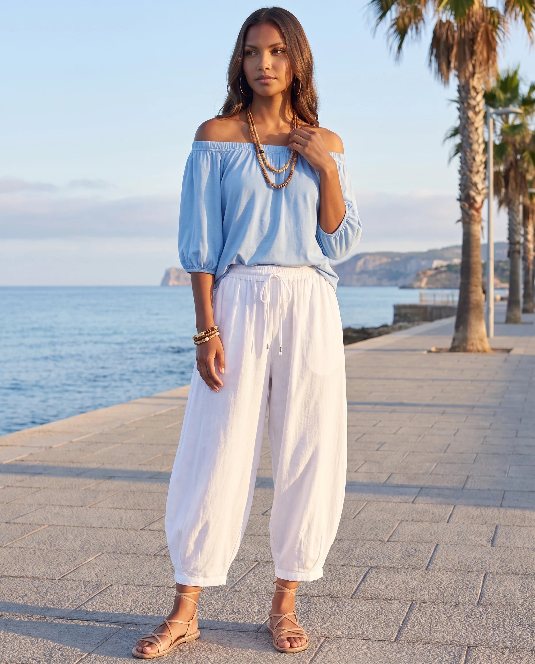 Ensemble epaules denudees et pantalon sarouel Bleu Ciel portee sur un front de mer au matin - Lorene | Zolena
