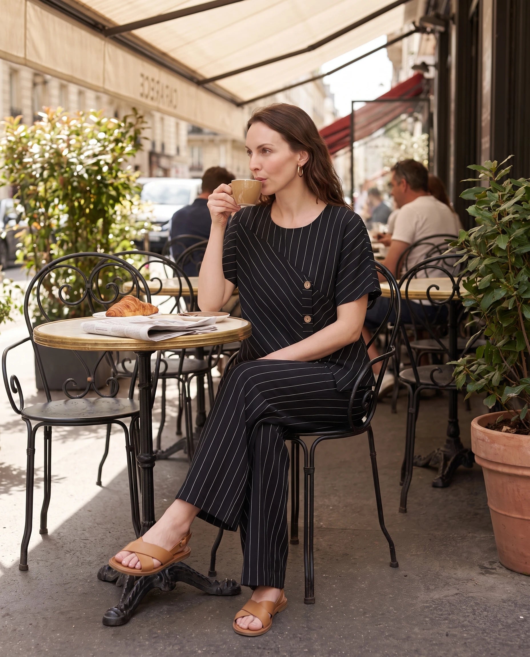 Ensemble top raye asymetrique et pantalon large Noir assise en terrasse de café - Amandine | Zolena