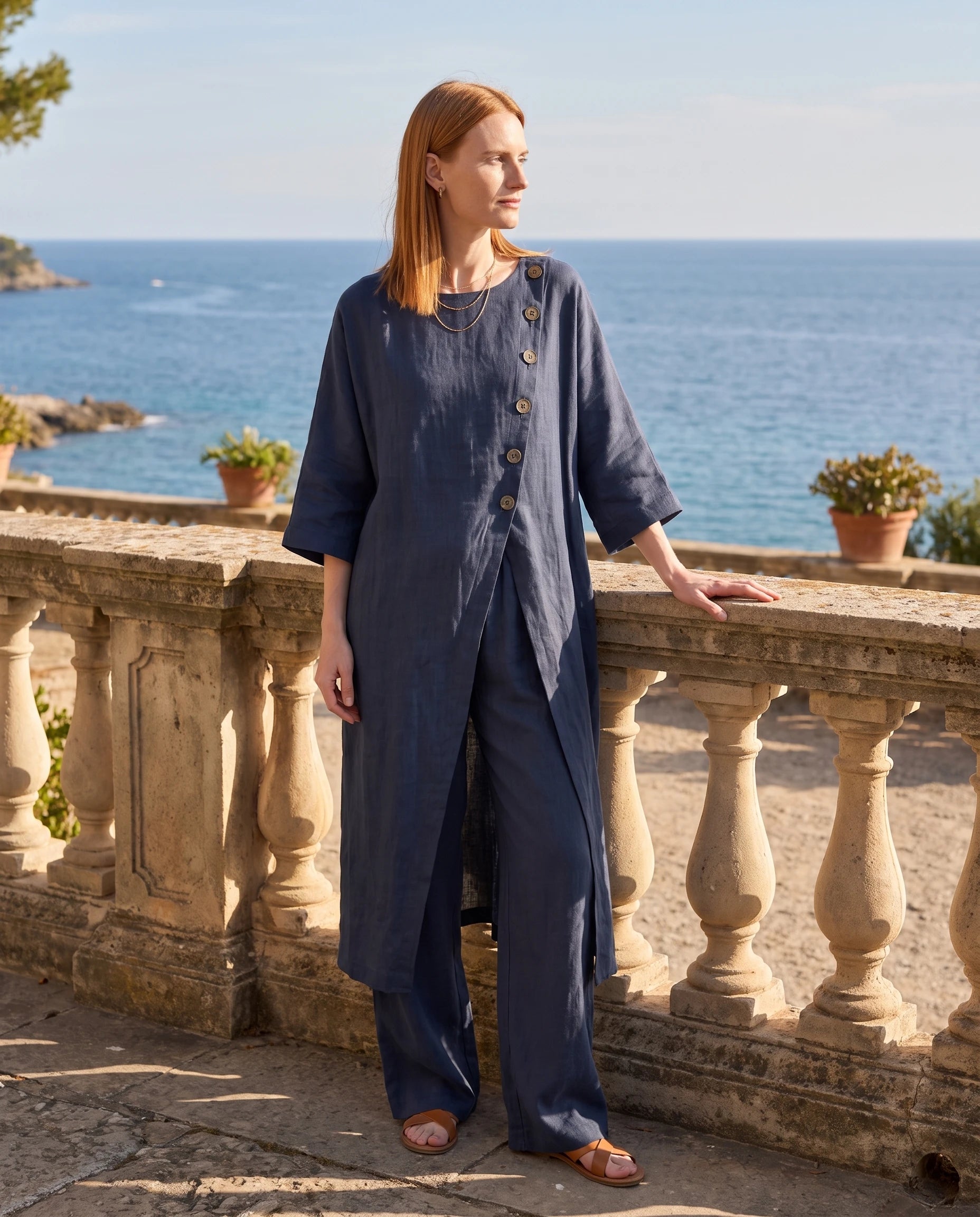 Ensemble tunique longue en lin et pantalon large Bleu Marine sur une terrasse de pierre vue mer - Ombeline | Zolena