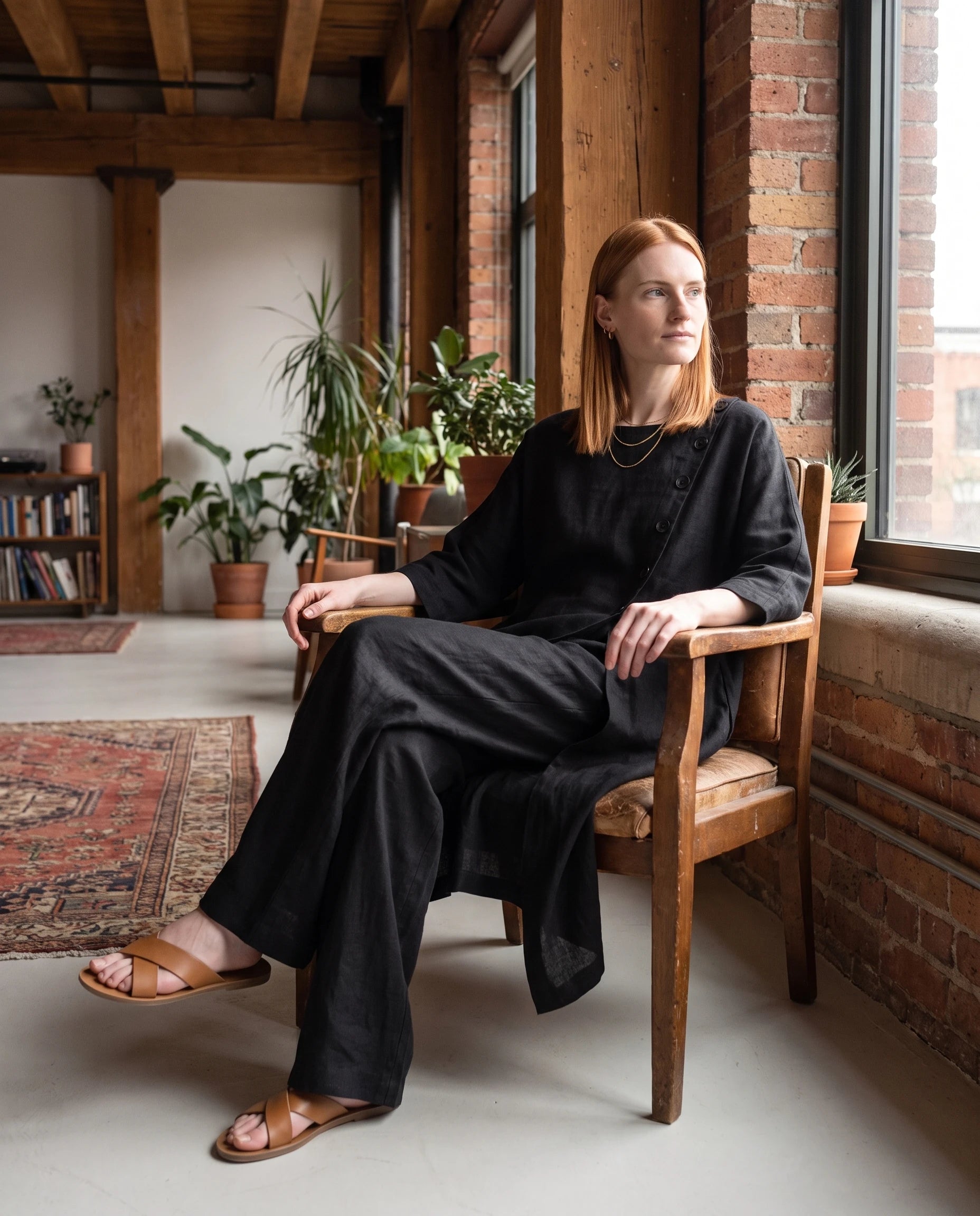 Ensemble tunique longue en lin et pantalon large Noir assise dans un loft chaleureux - Ombeline | Zolena